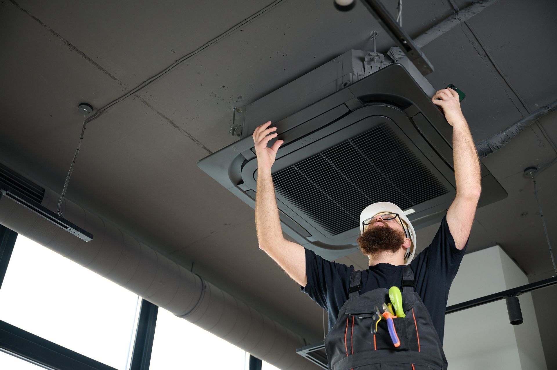 Professional AC contractor servicing ceiling air conditioning equipment.