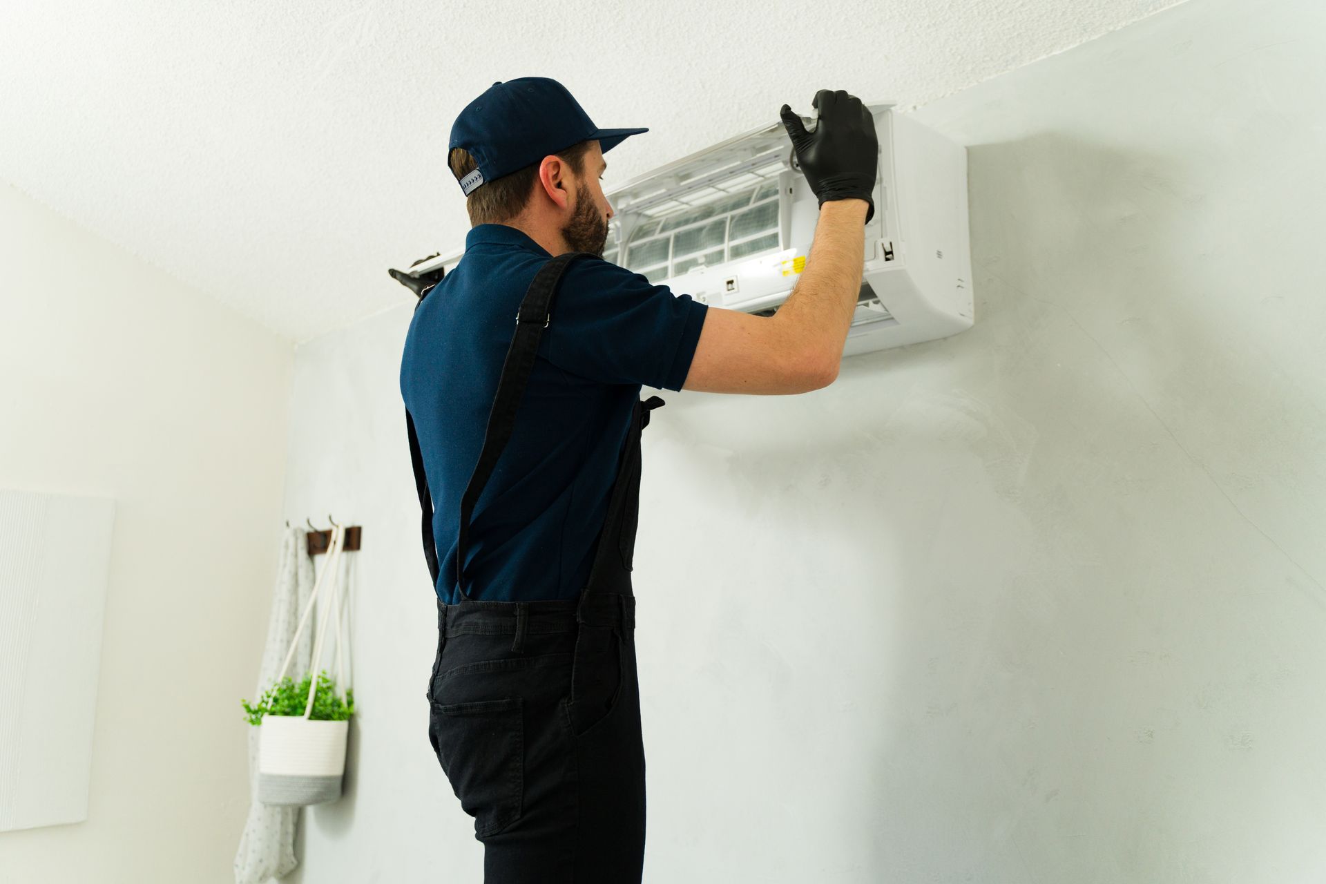Technician servicing wall-mounted AC unit, ensuring efficient cooling and clean airflow.