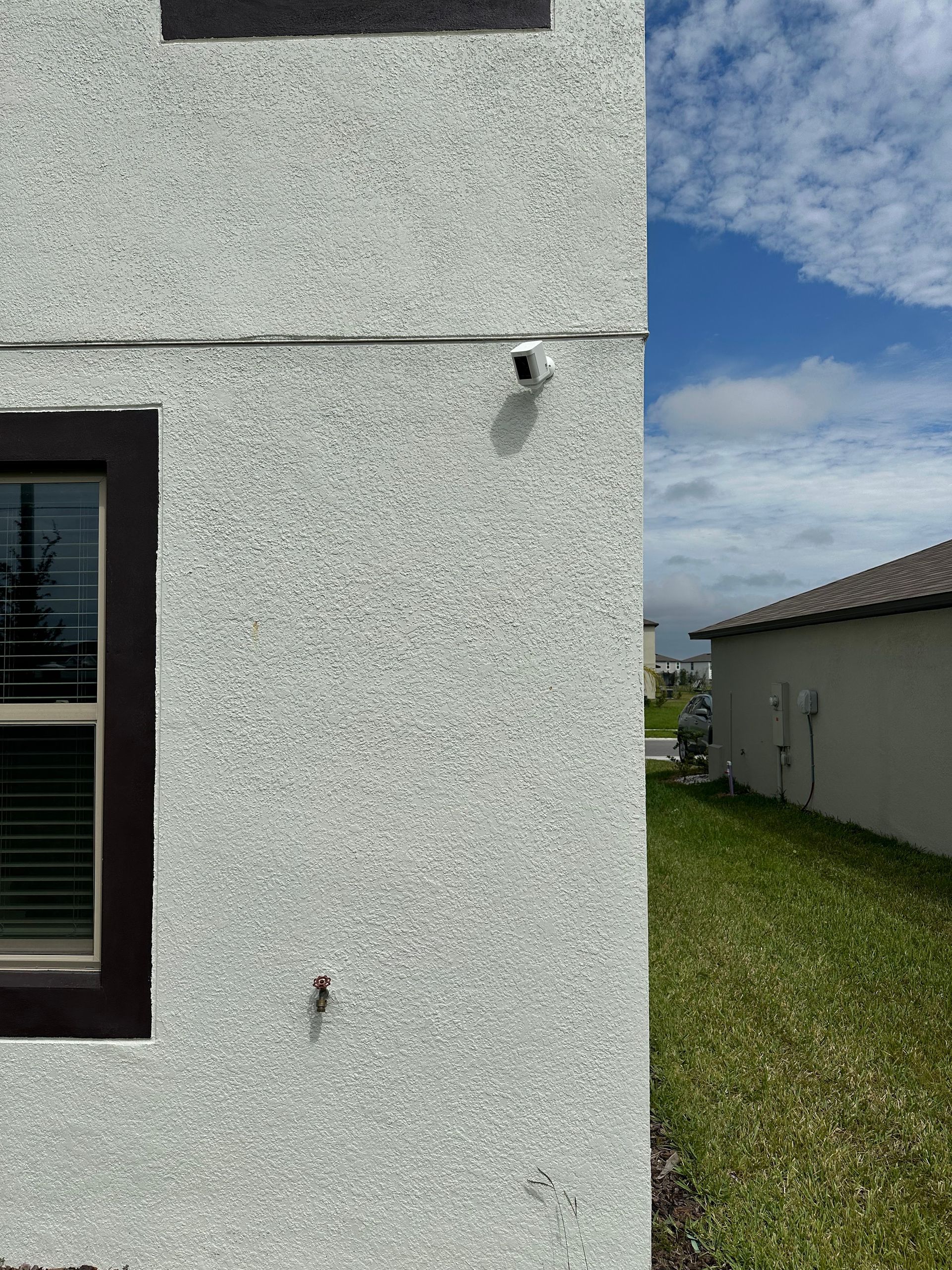 A white house with a window and a camera on the side of it.
