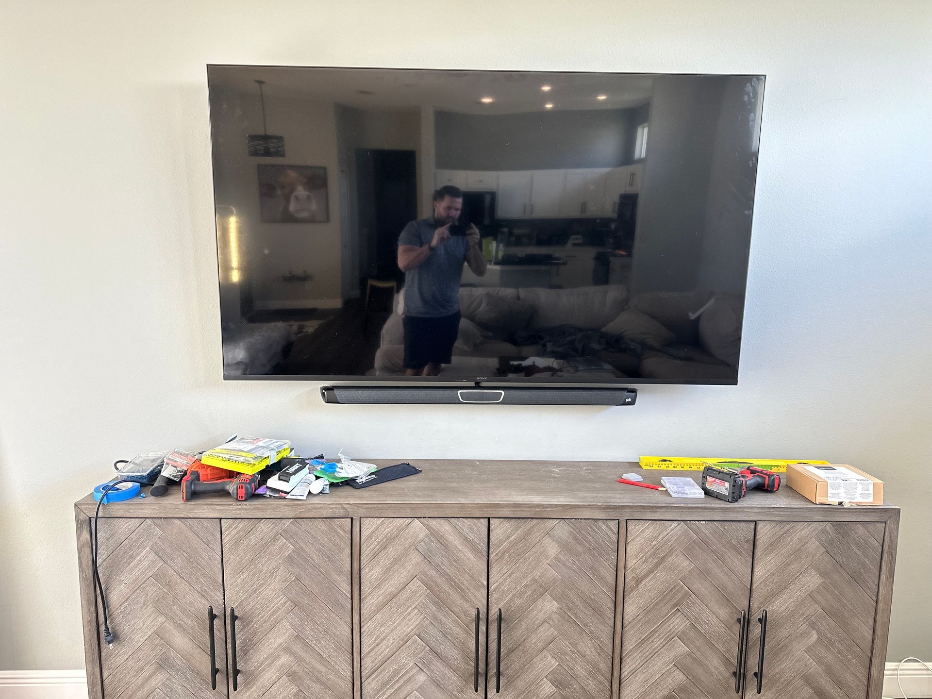 A man is taking a picture of himself in a living room in front of a flat screen tv.