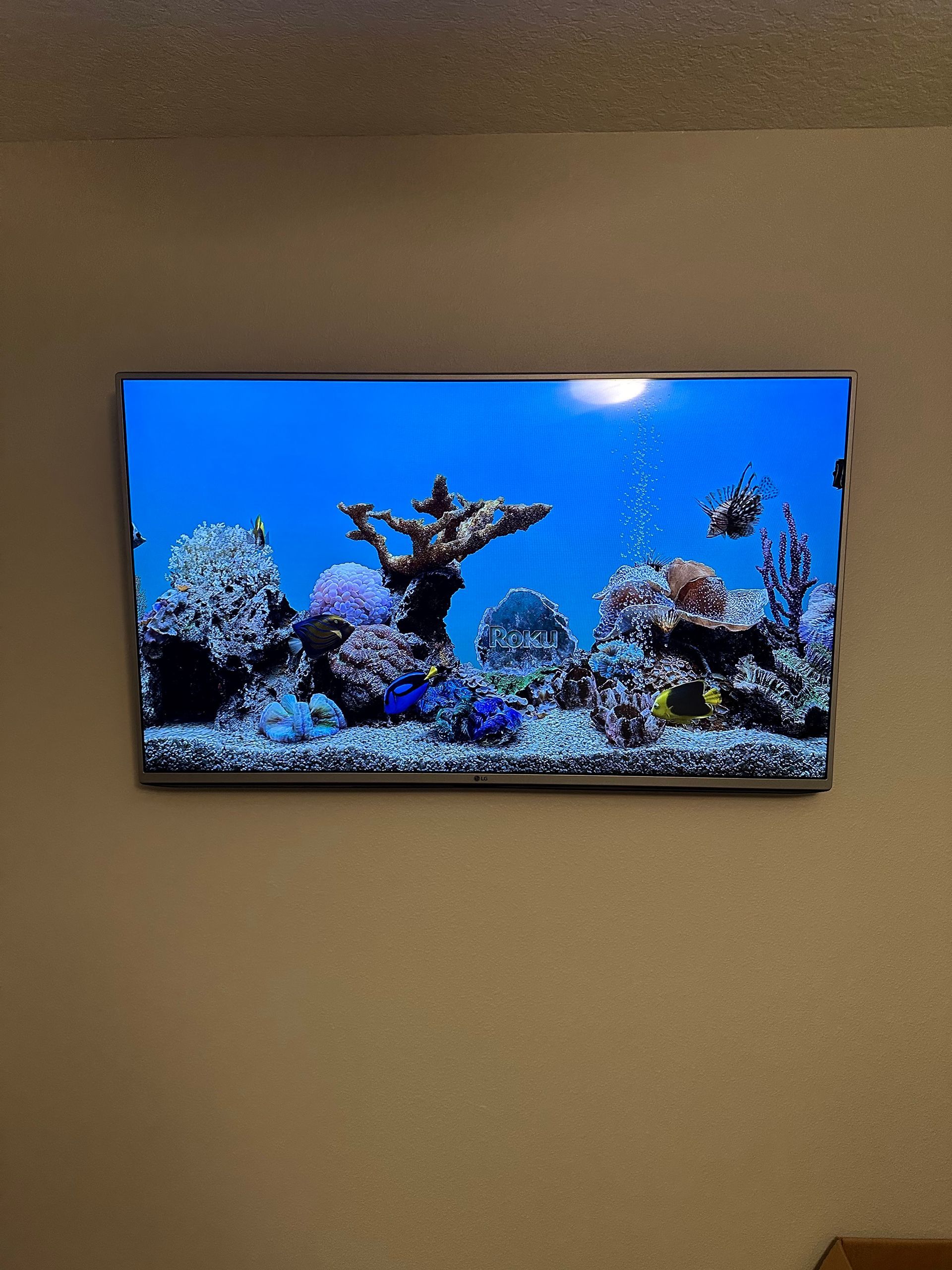 A flat screen tv is hanging on a wall with a picture of a coral reef on it.