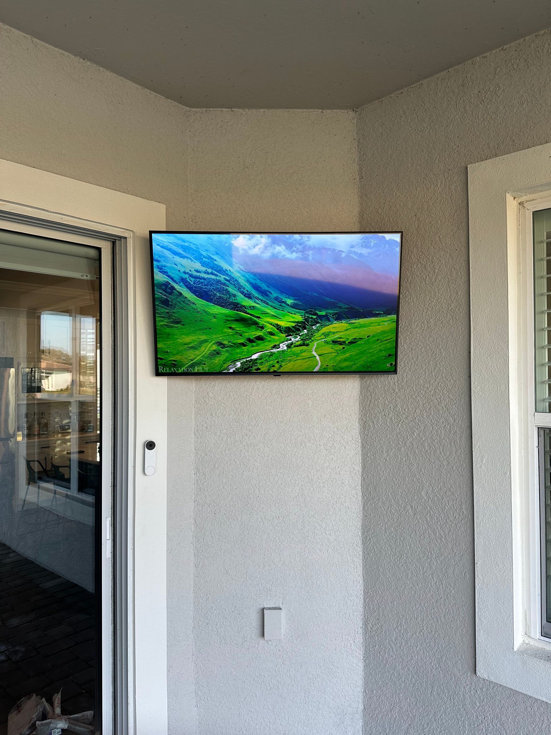 A flat screen tv is mounted on a wall next to a window.