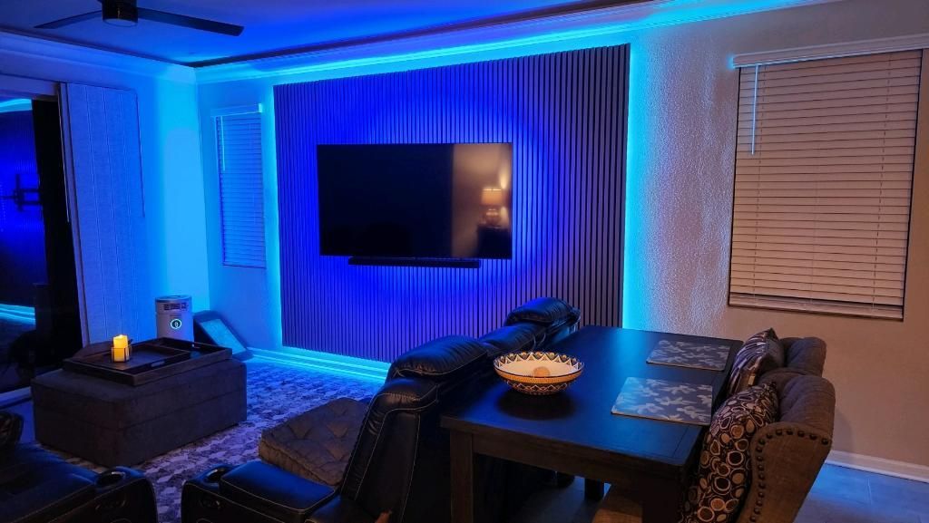 A living room with a couch , table , chairs and a flat screen tv.