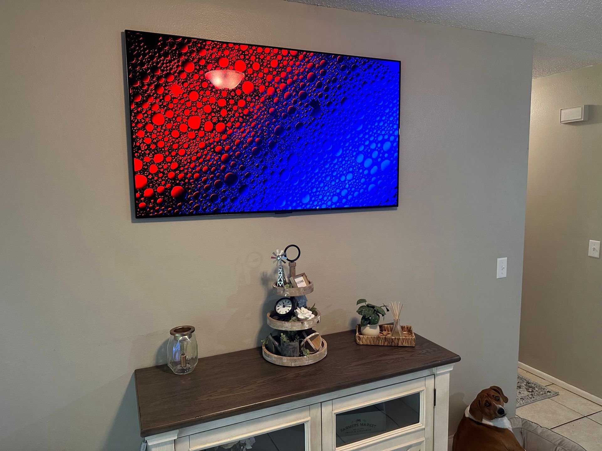 A large painting is hanging on a wall above a dresser in a living room.