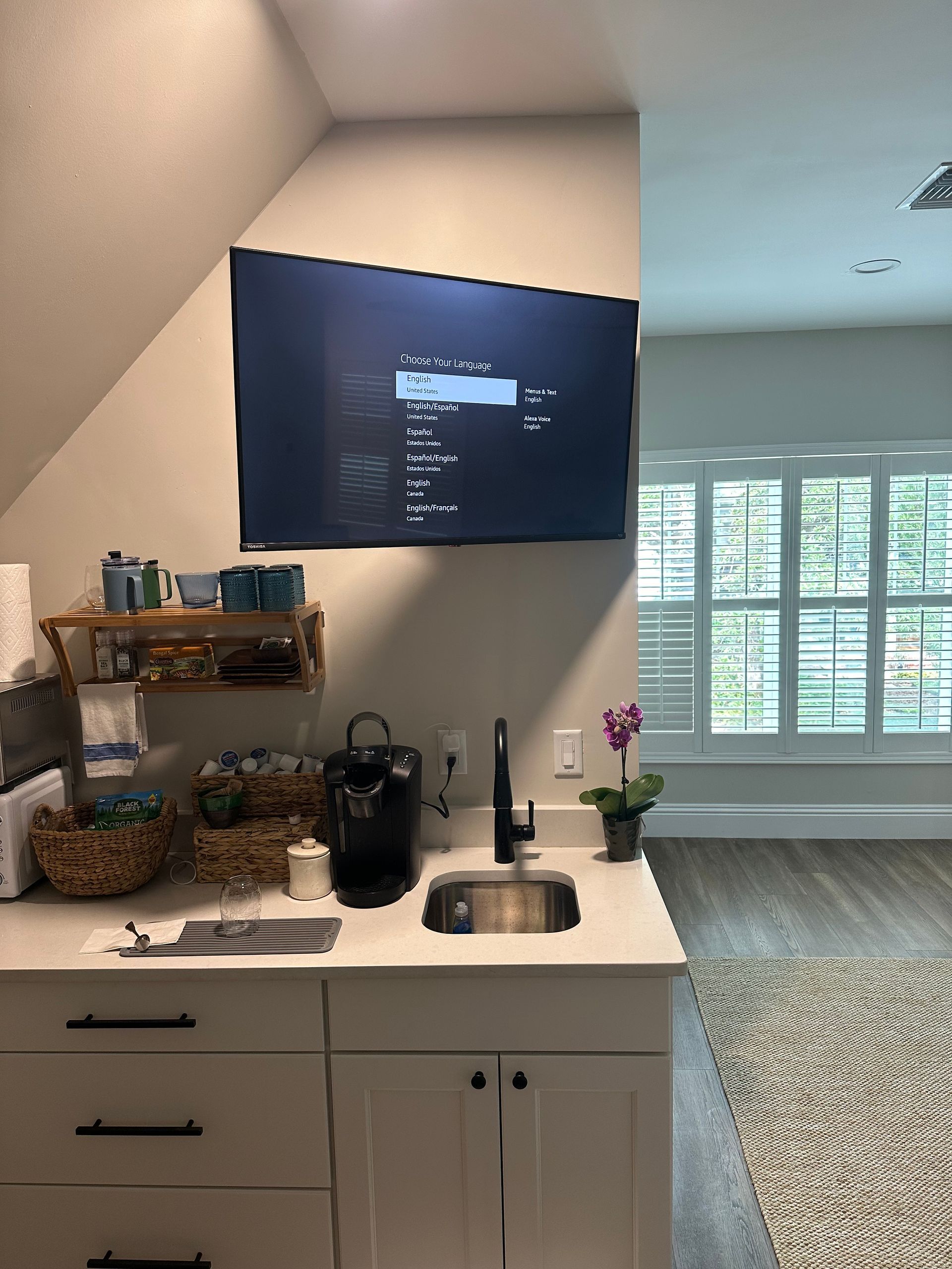 A kitchen with a sink and a flat screen tv on the wall.