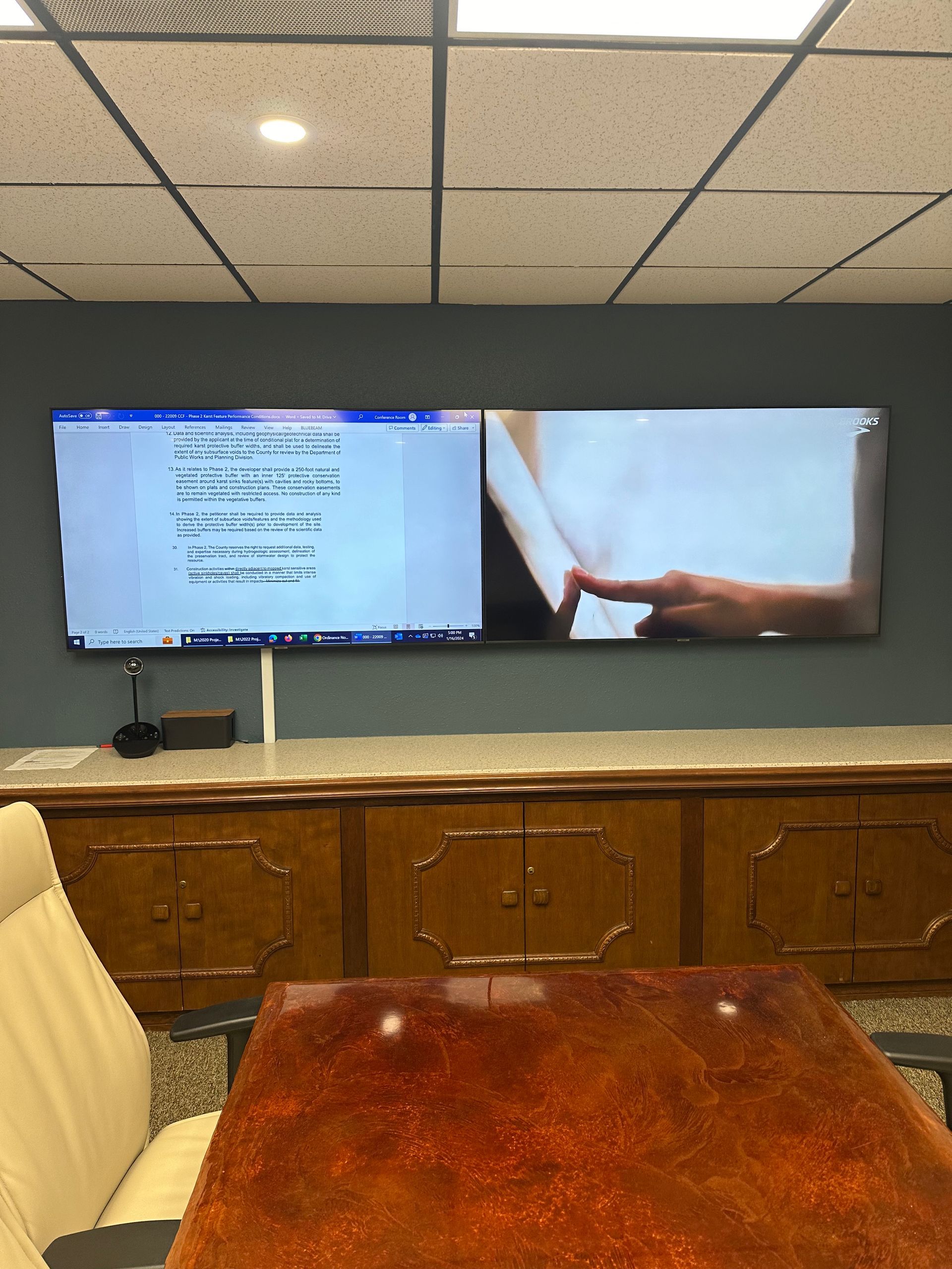 A conference room with two monitors on the wall and a table
