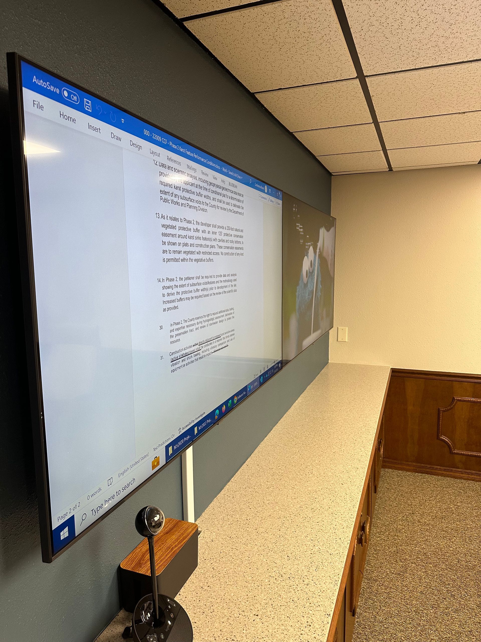 A computer monitor is hanging on a wall next to a webcam.