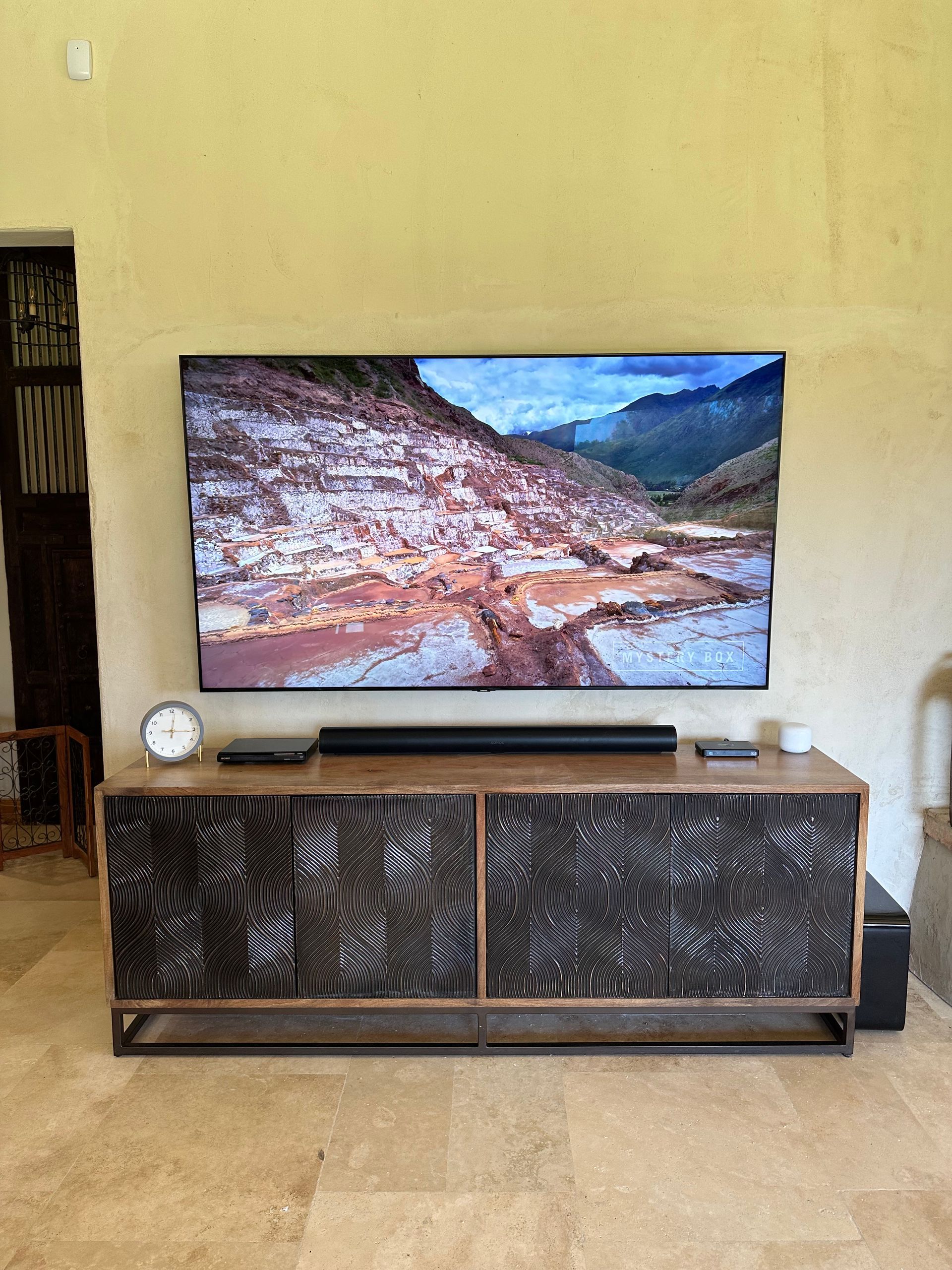 A flat screen tv is hanging on a wall above a wooden entertainment center.