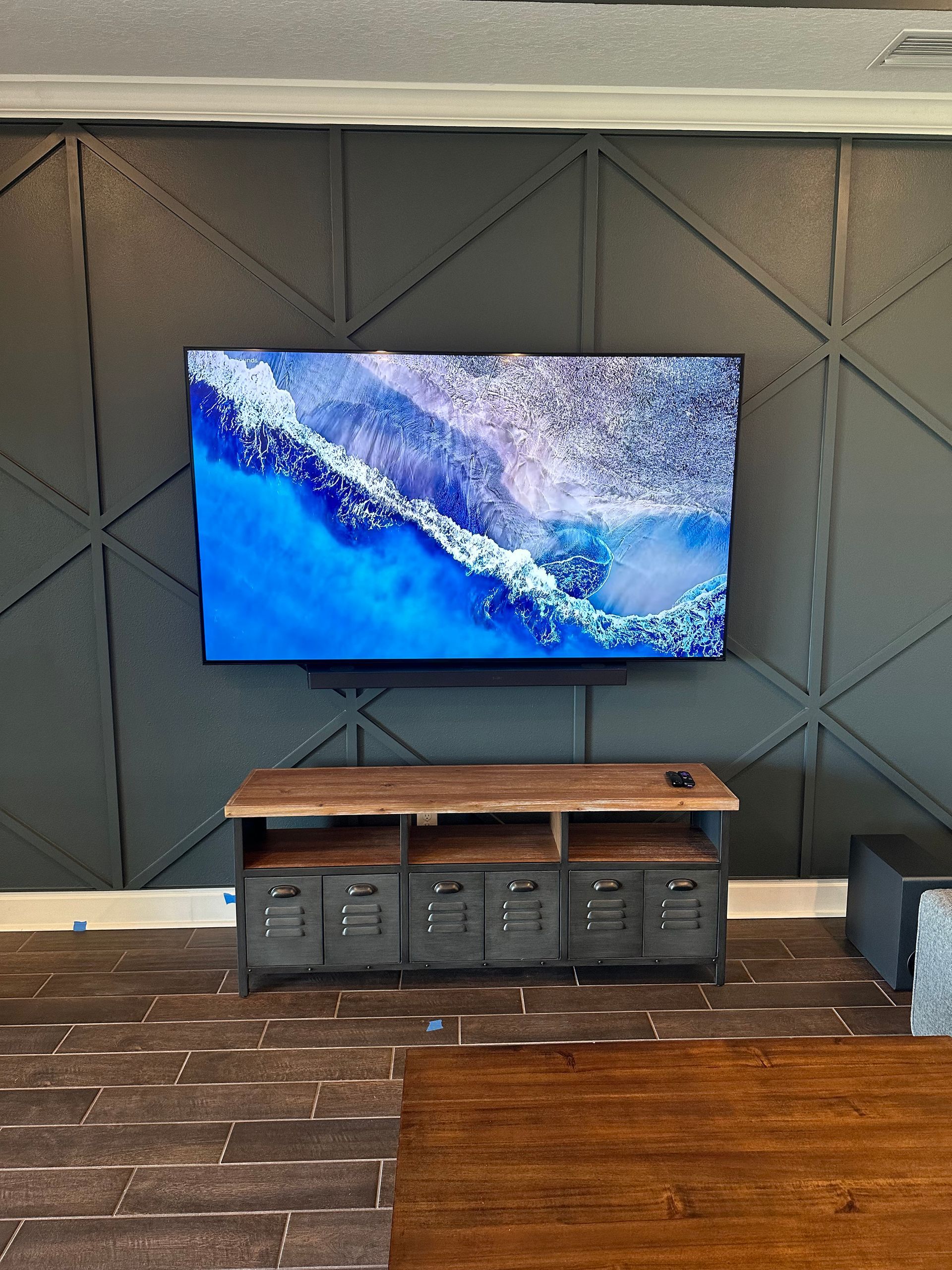 A flat screen tv is hanging on a wall above a wooden entertainment center.