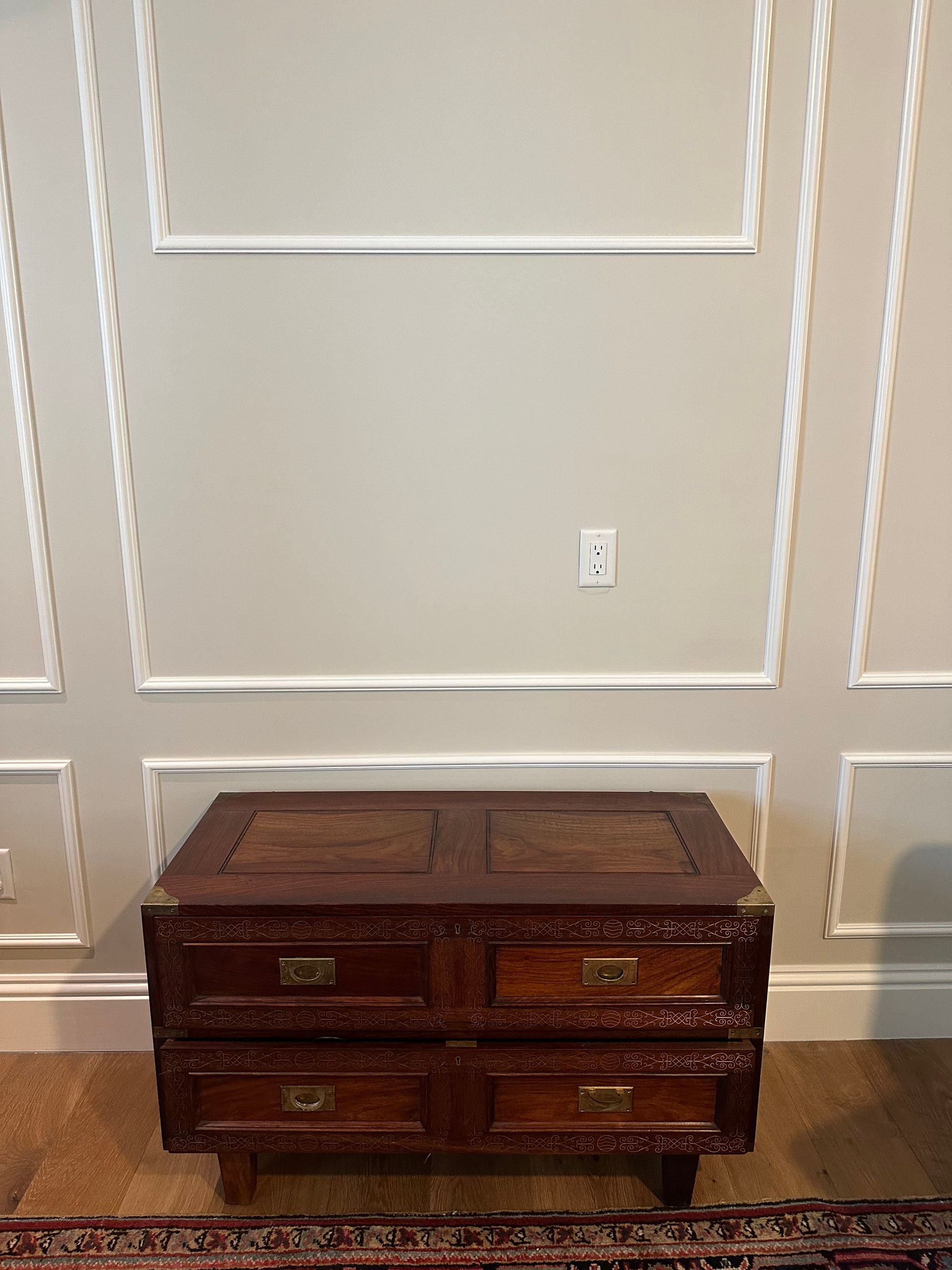 A wooden chest of drawers is sitting in front of a wall.