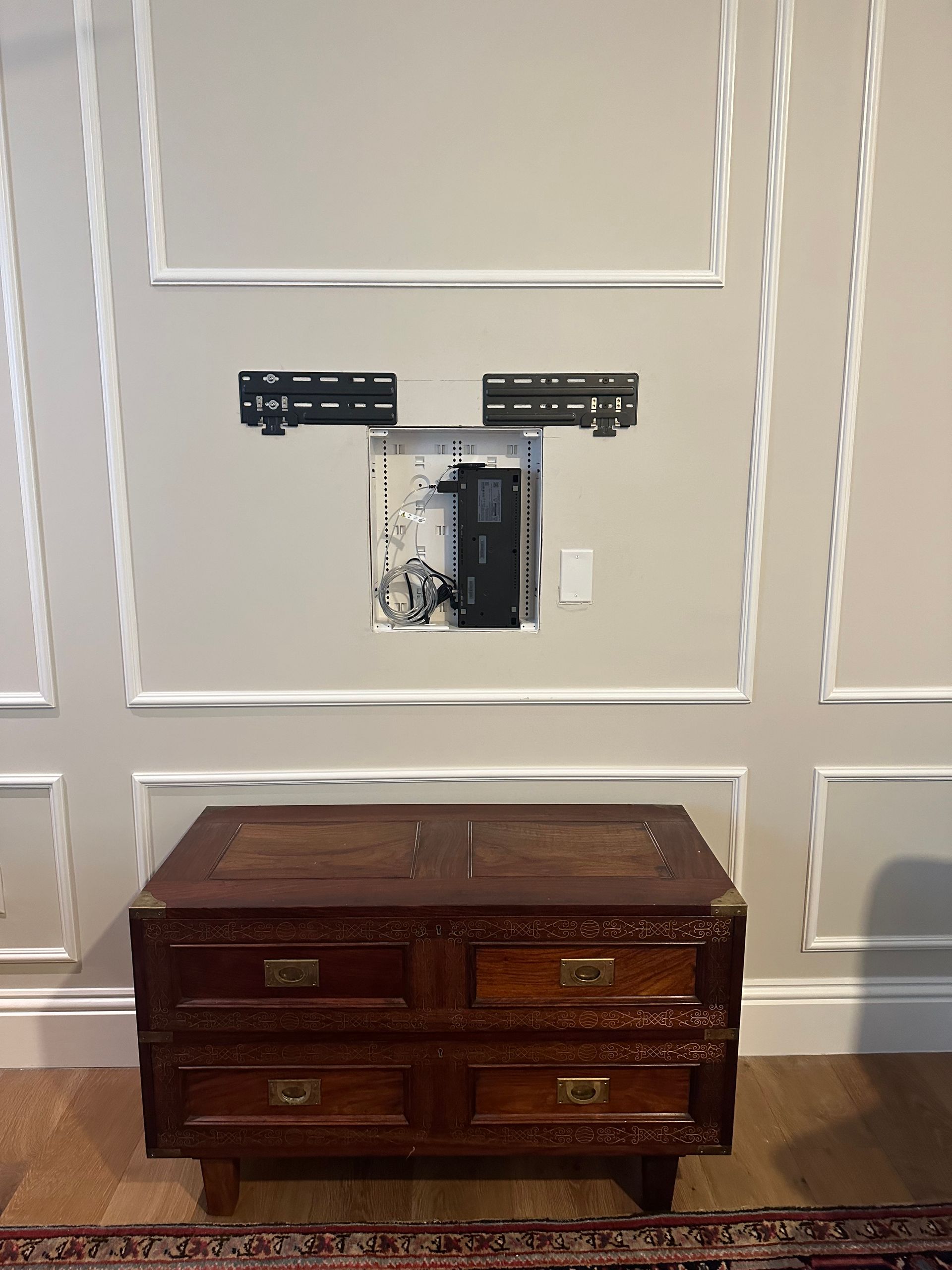 A wooden dresser is sitting in front of a wall mounted television.