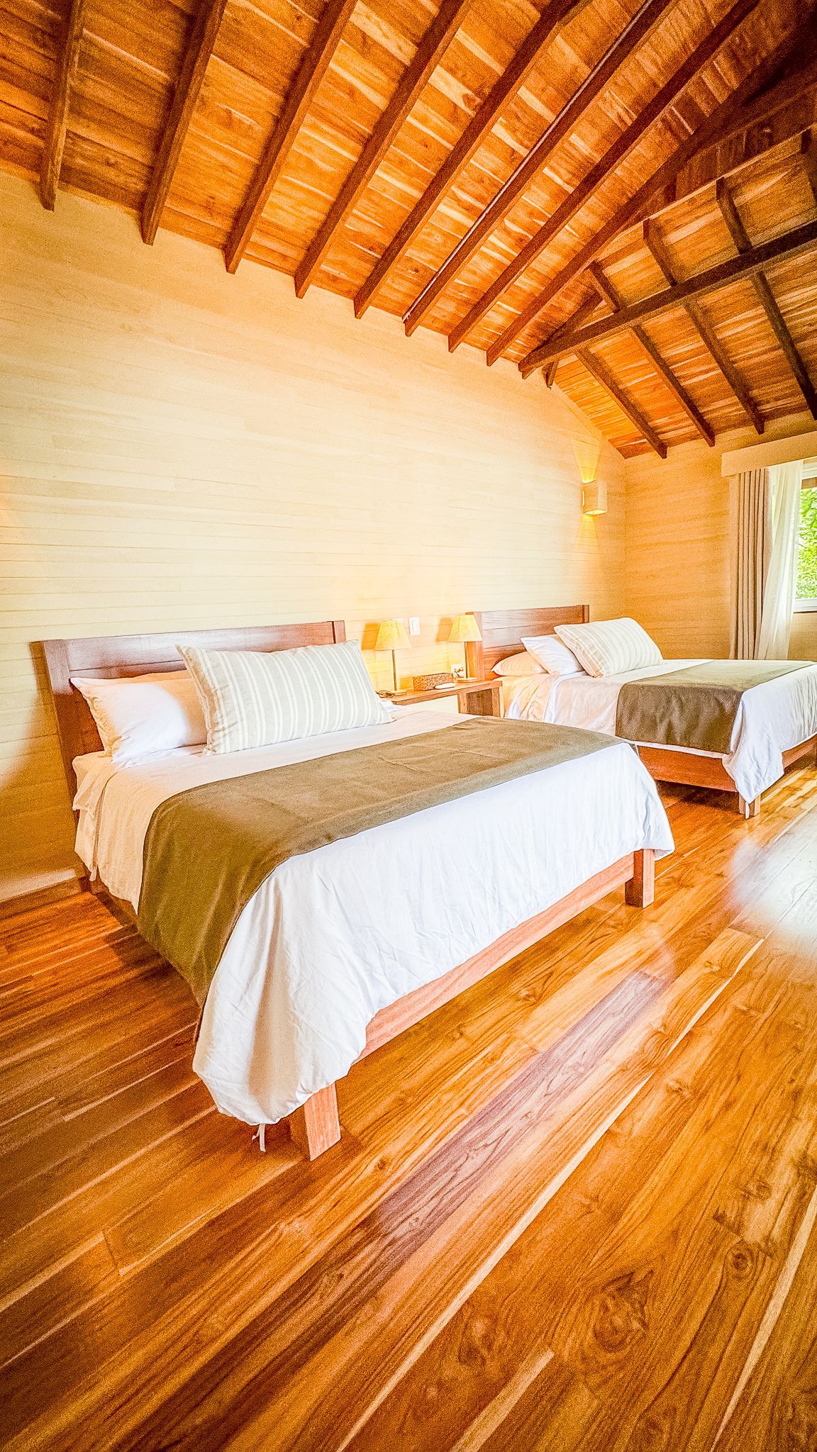 A bedroom with two beds and a wooden floor.