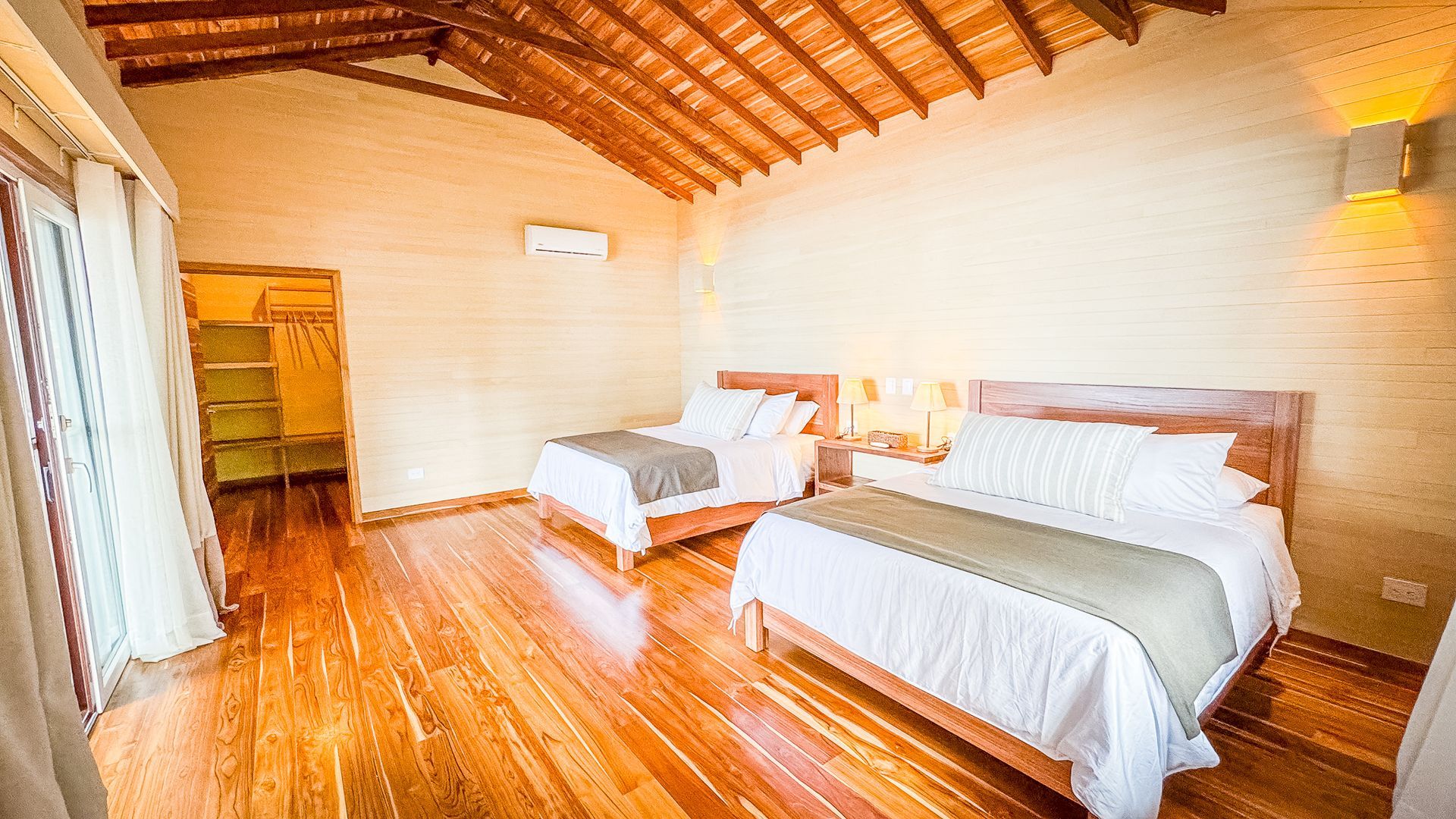 A hotel room with two beds and a wooden floor.