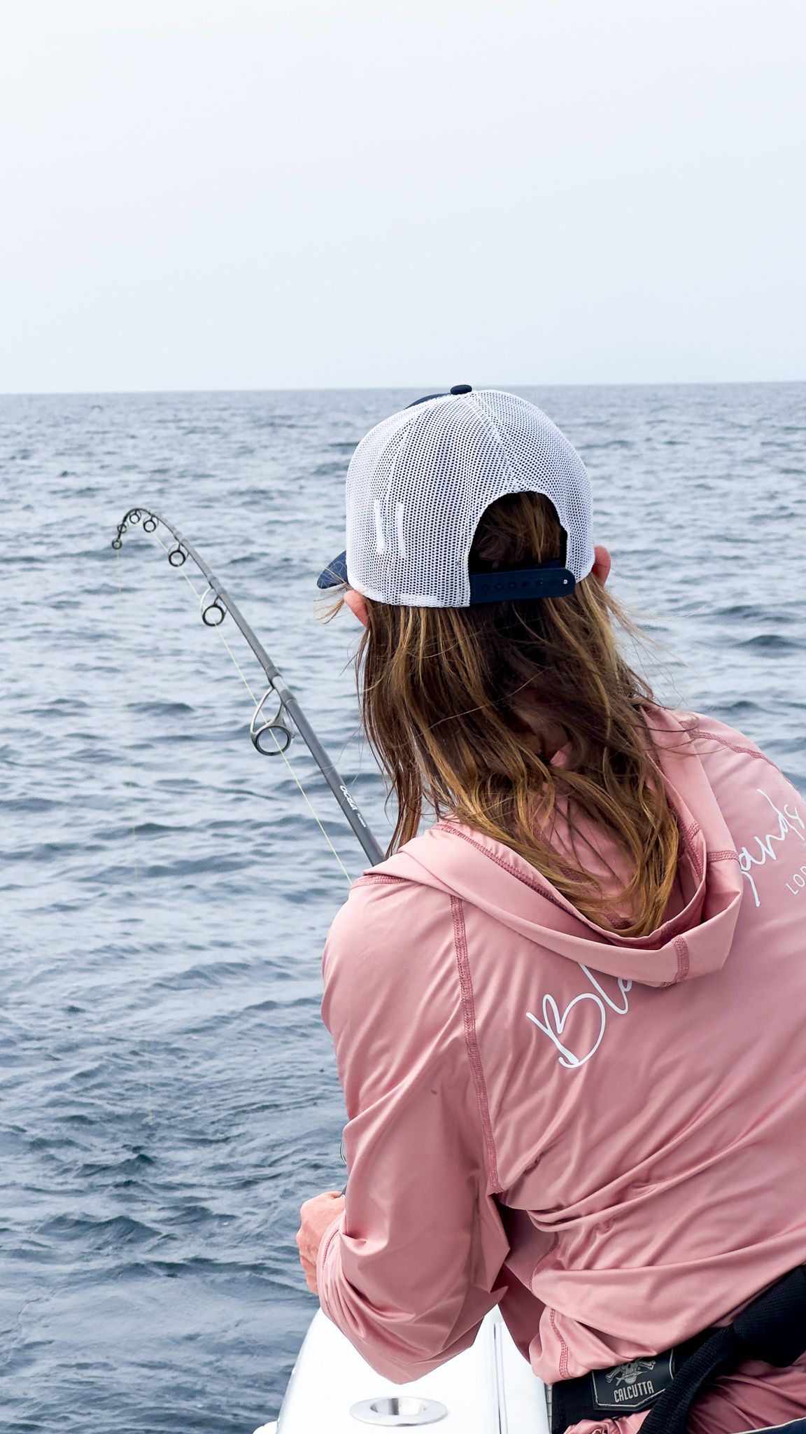 A woman is fishing in the ocean on a boat.