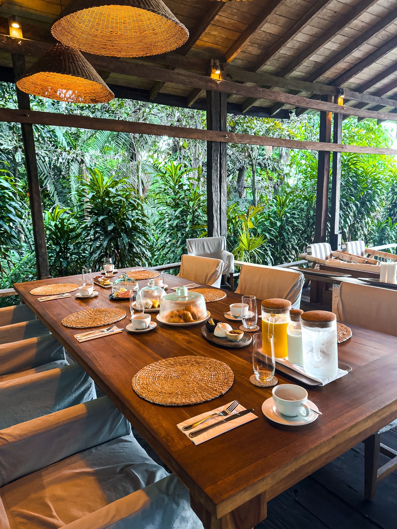 A long wooden table with plates of food and drinks on it.