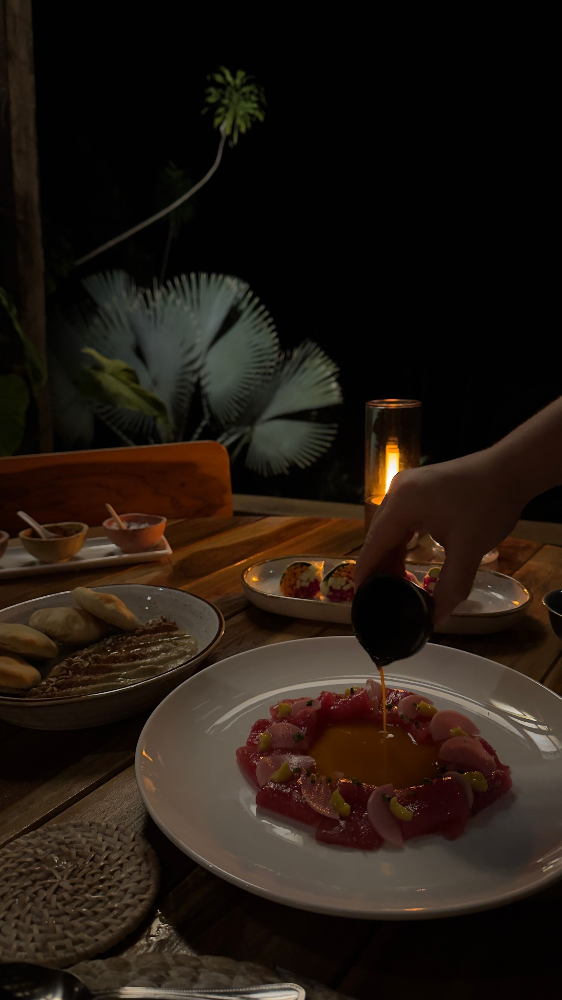 A person is pouring oil on a plate of food on a table.
