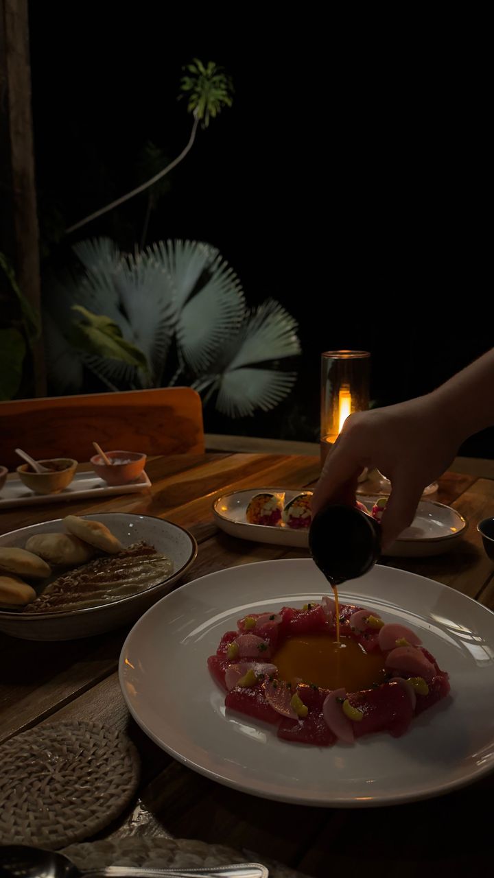 A person is pouring oil on a plate of food on a table.