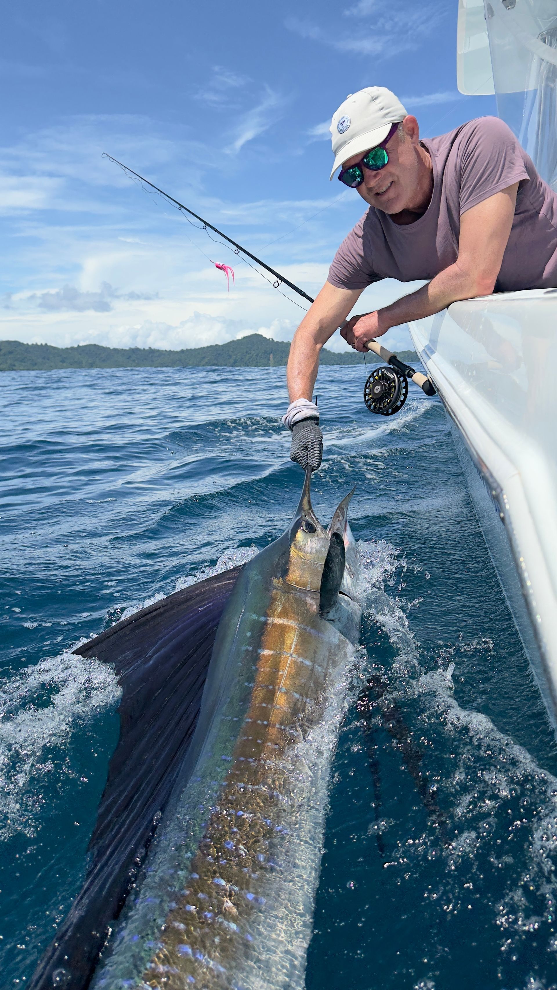 A man is sitting on a boat holding a large fish.