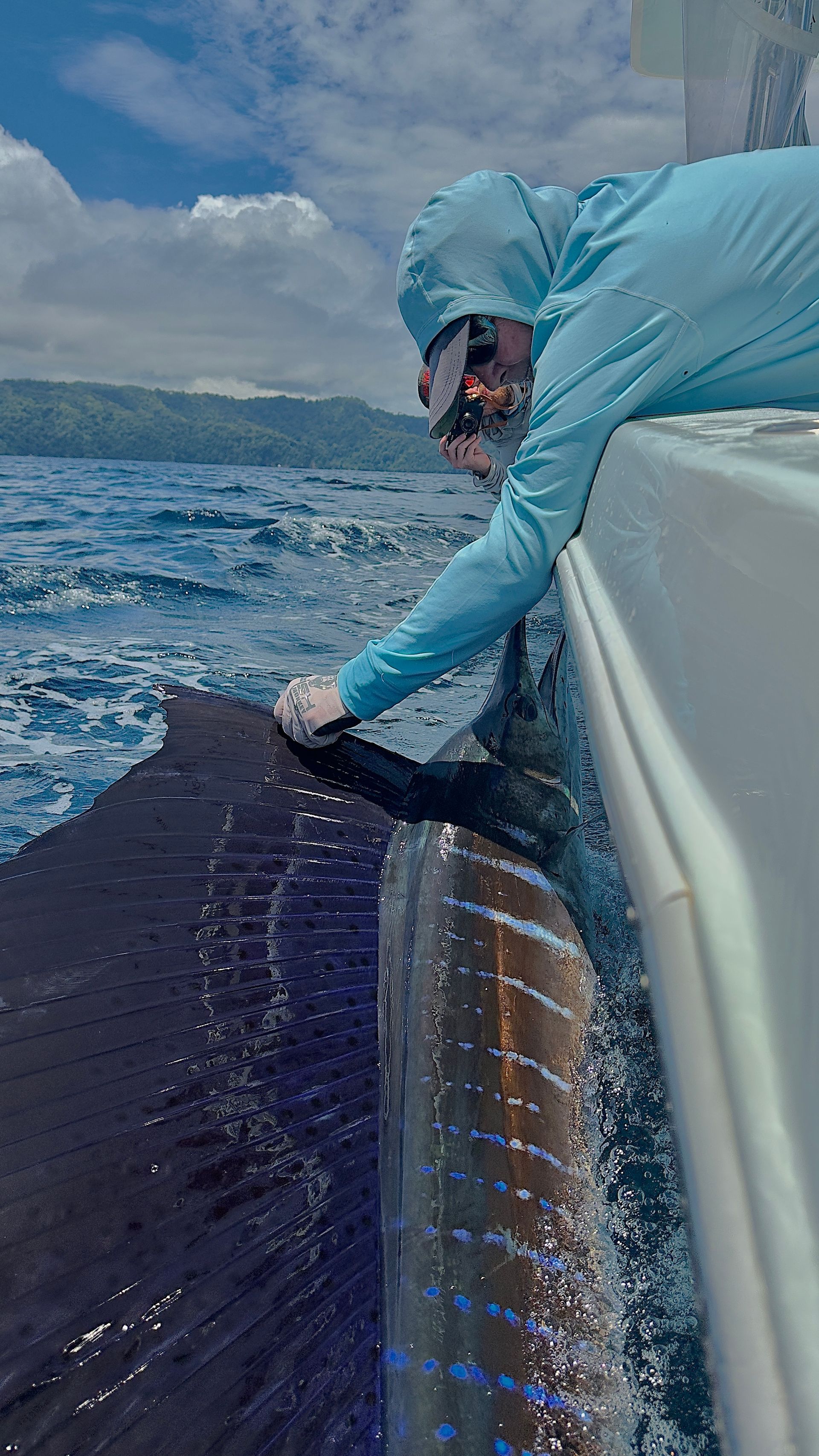 A man is standing on the side of a boat in the ocean.