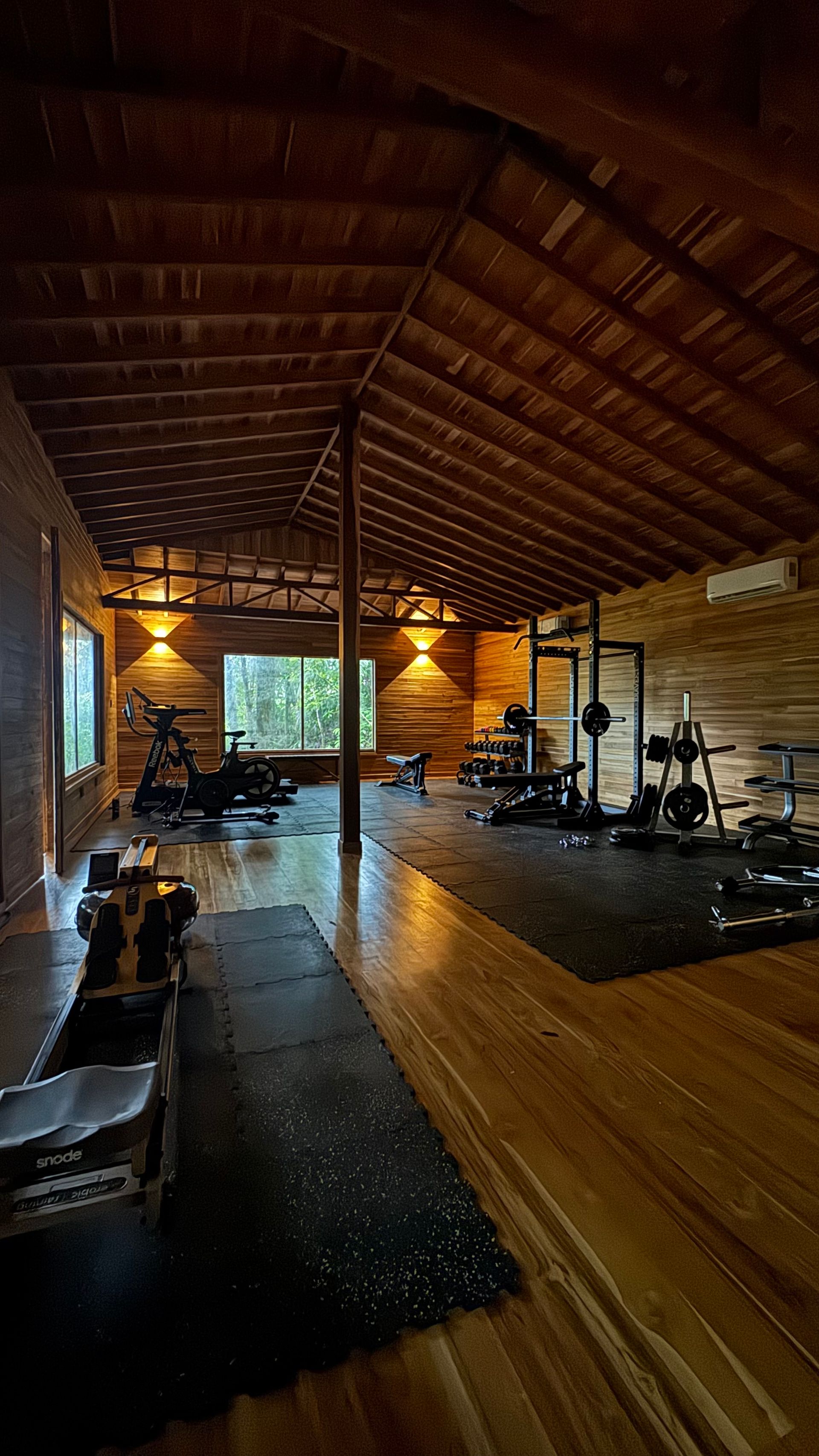 A large wooden gym with lots of equipment and a wooden ceiling.