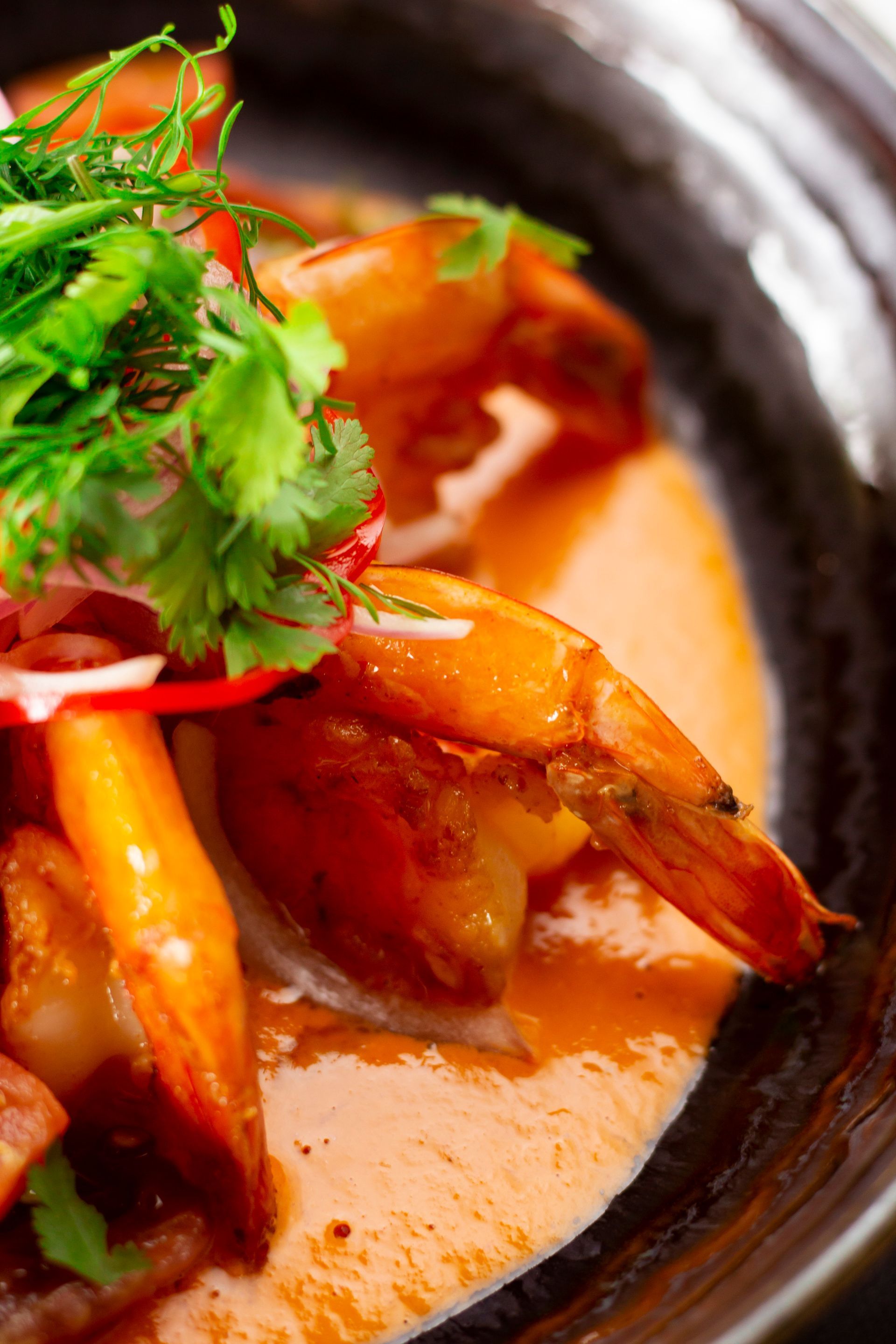 Two plates of food are sitting on a wooden table next to a bowl of food.