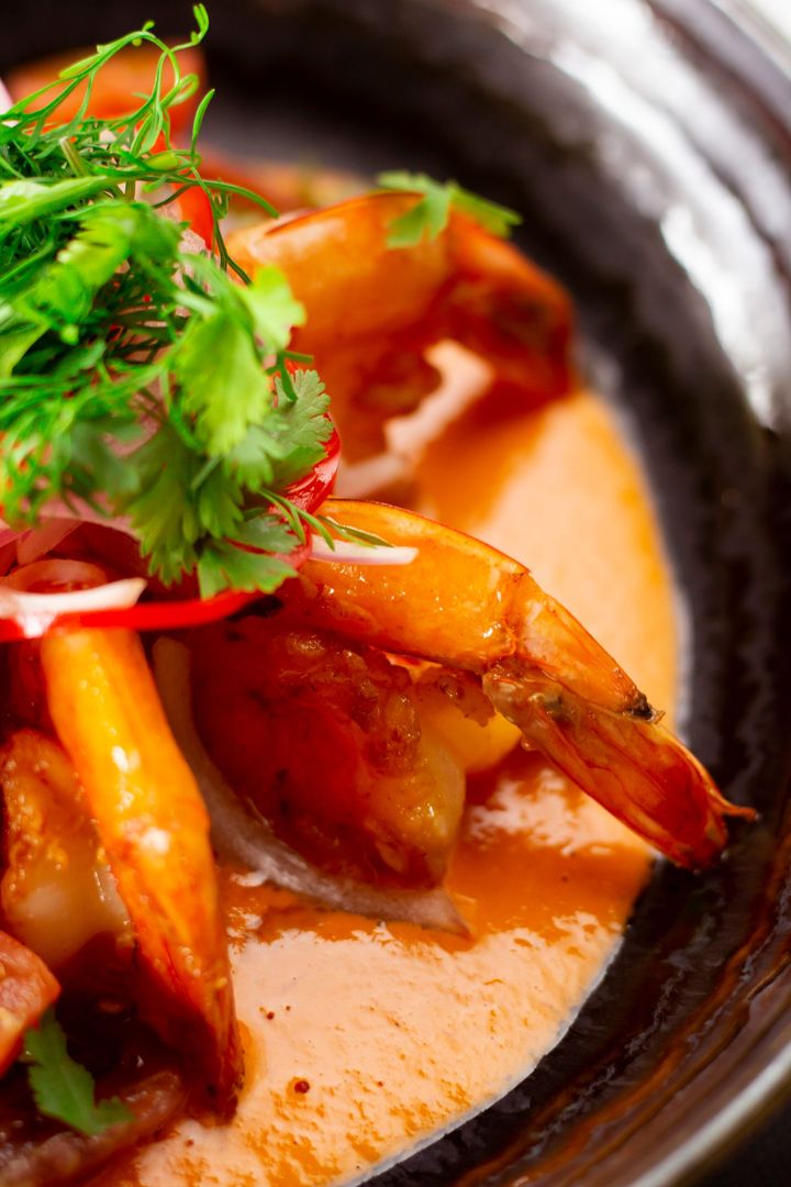 Two plates of food are sitting on a wooden table next to a bowl of food.