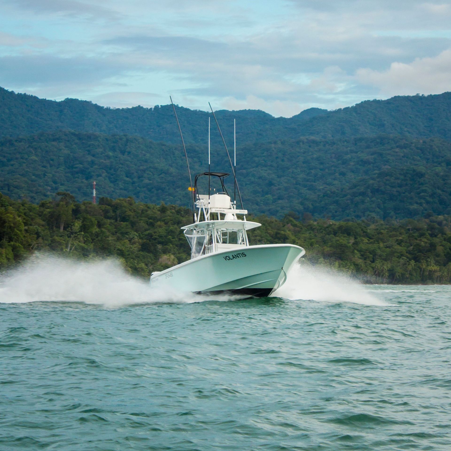 A large white boat is going through the water with mountains in the background