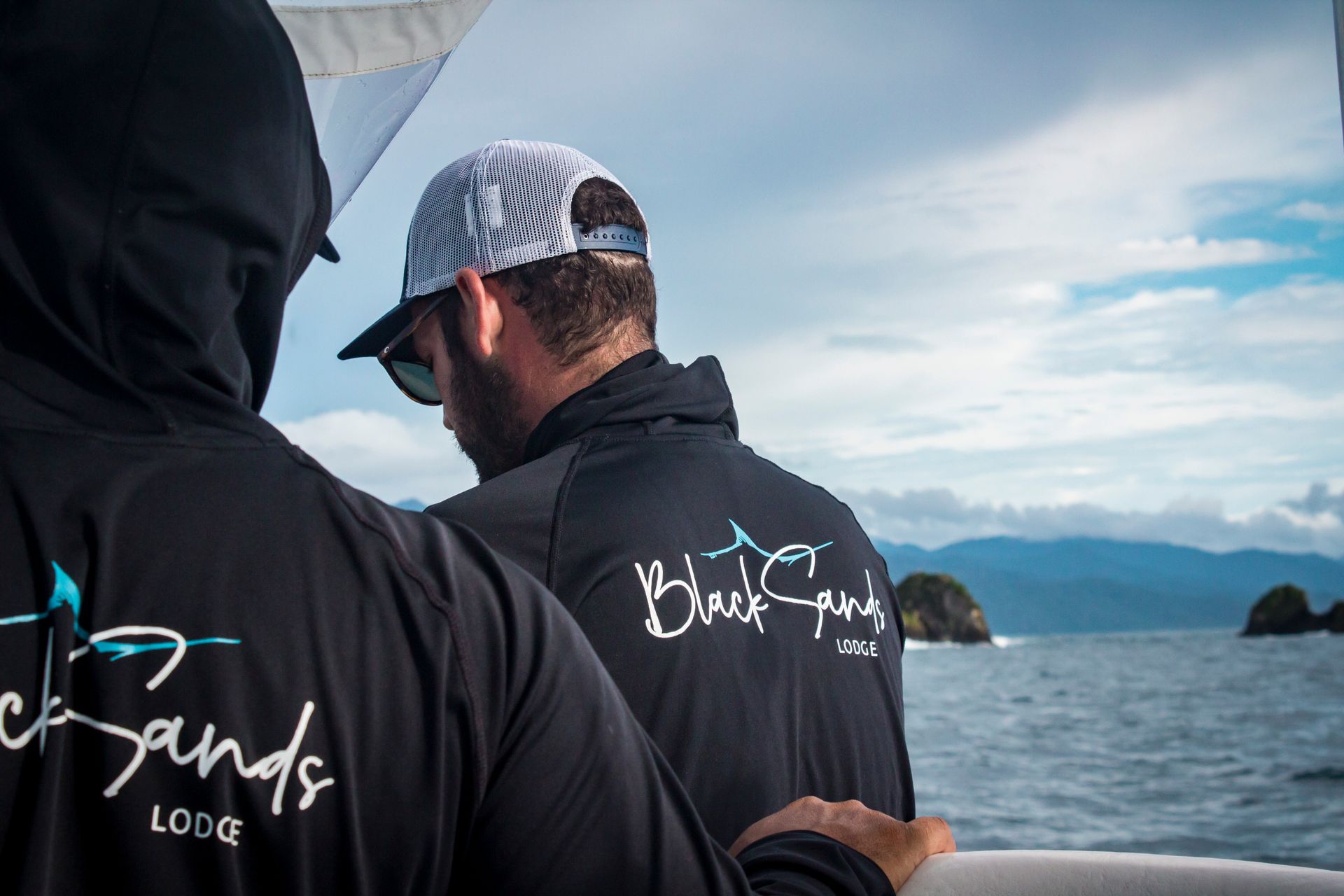 Two men are standing on a boat looking at the ocean.