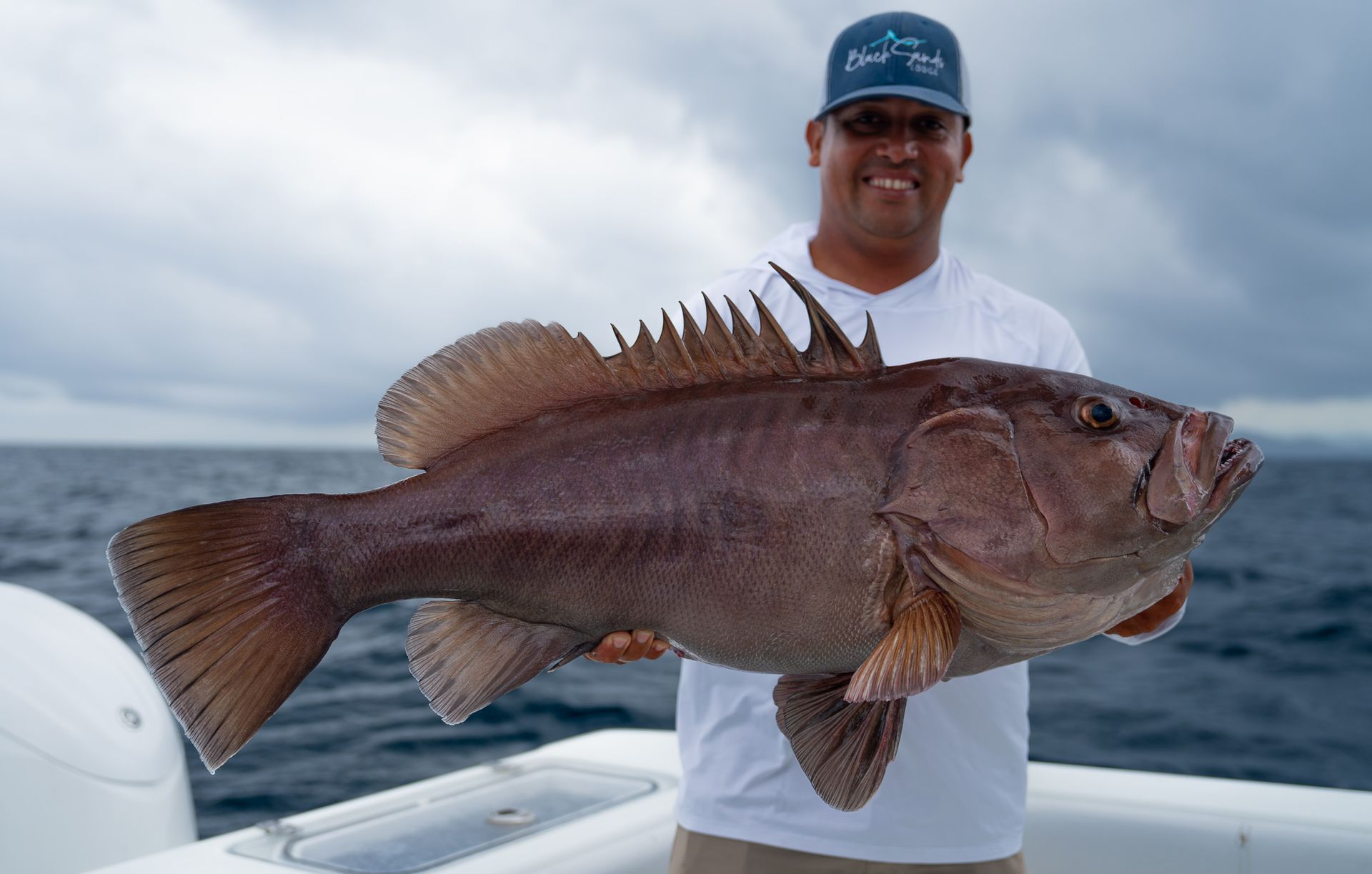 A man is holding a large fish on a boat.