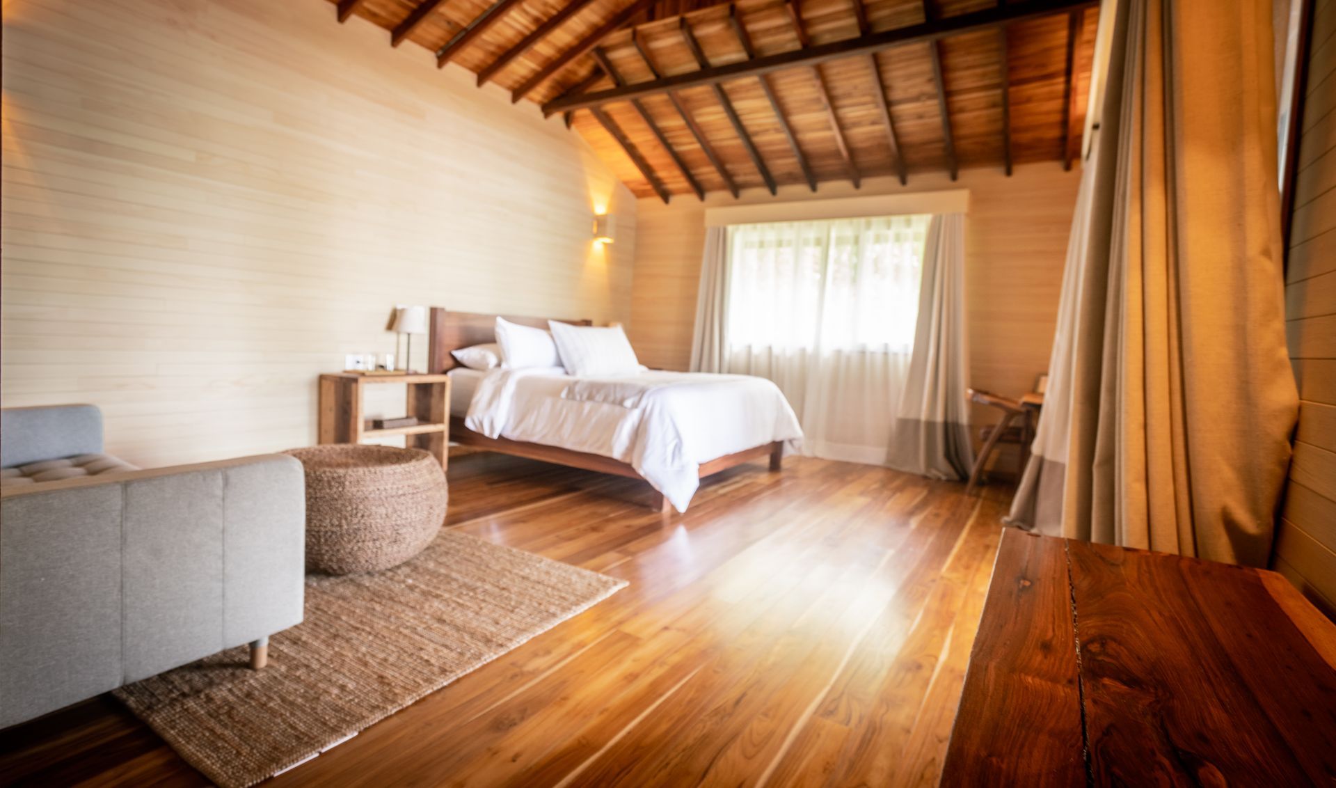 A bedroom with a bed , chairs , and a wooden floor.