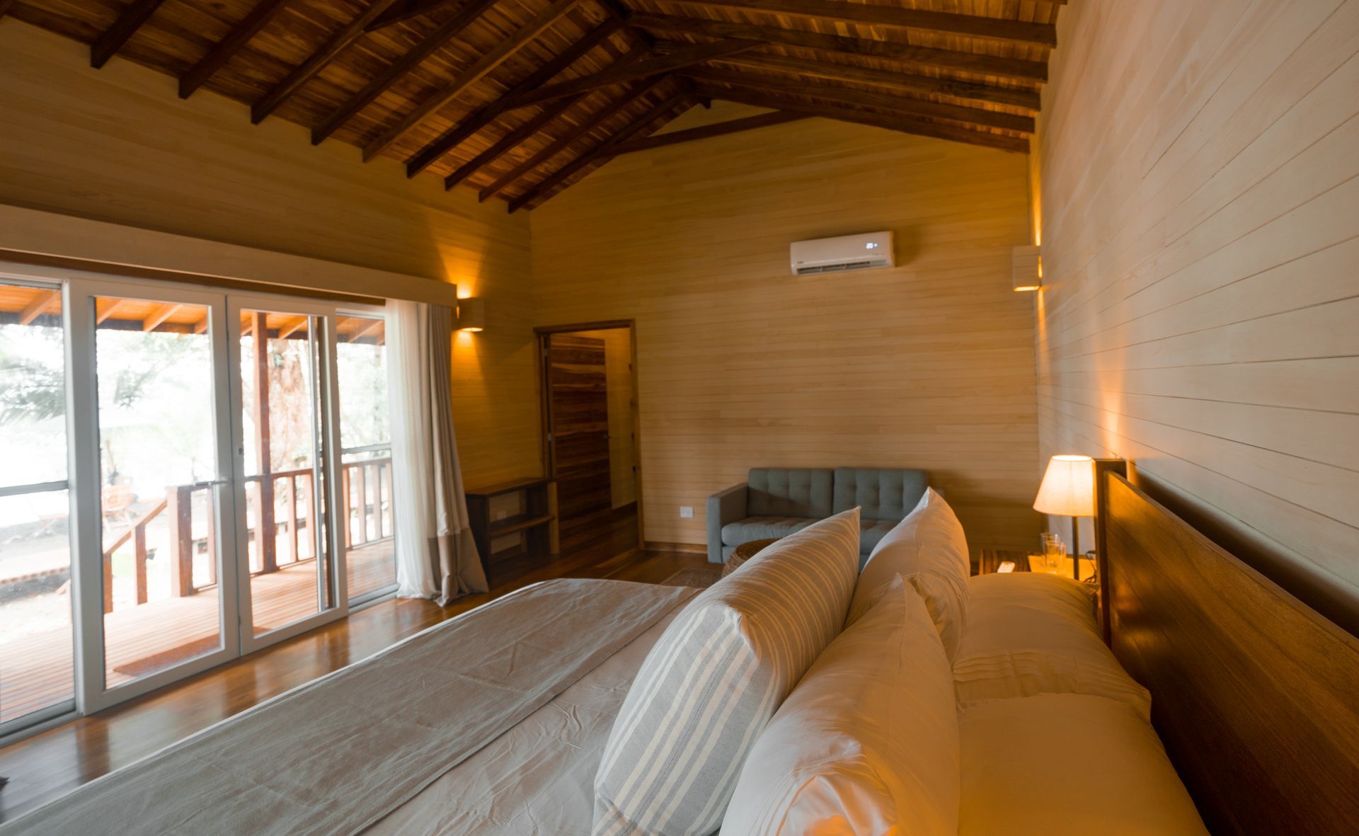 A bedroom with two beds , a desk and a sliding glass door.