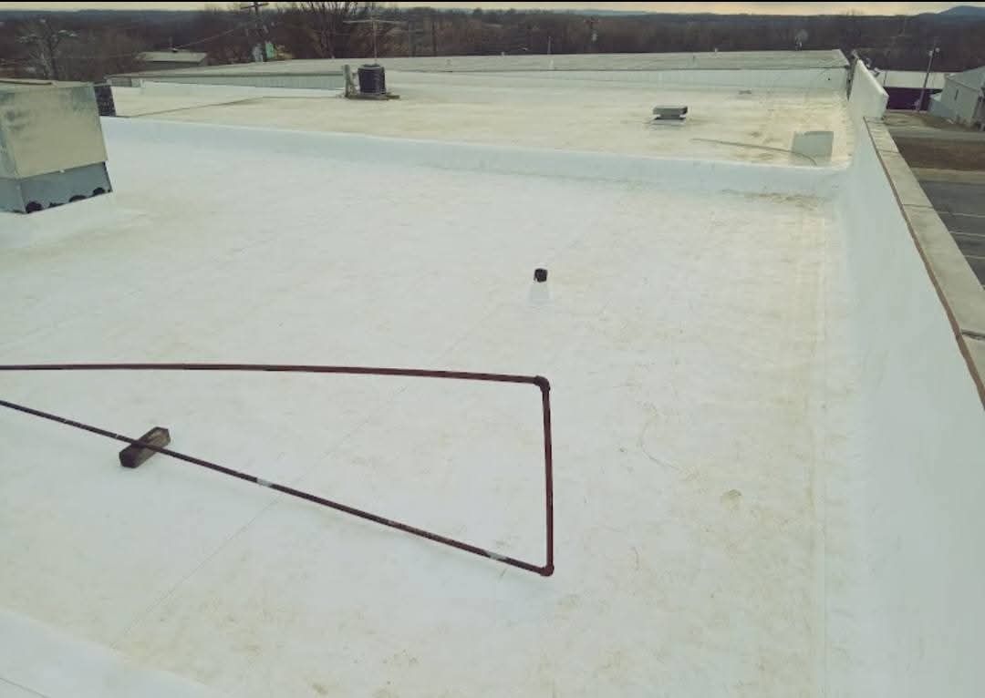 White flat commercial roof with copper pipe and vent structures.