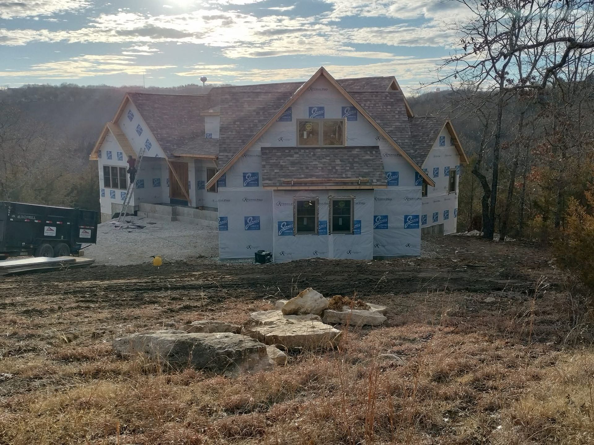 House under construction on a hillside, wrapped in blue protective sheathing.