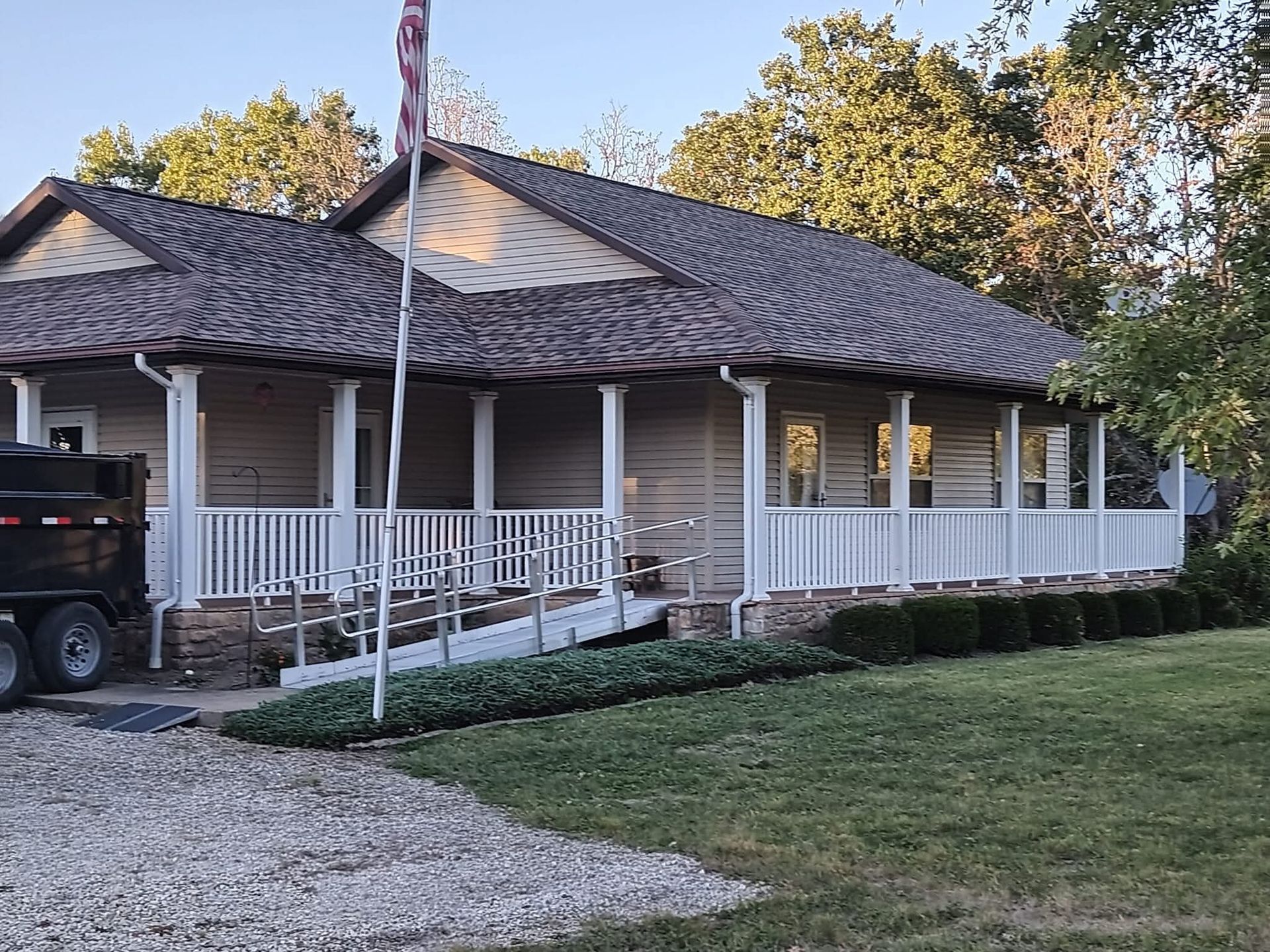 Exterior of a light brown building with white trim, porch, and a wheelchair ramp. An American flag flies.