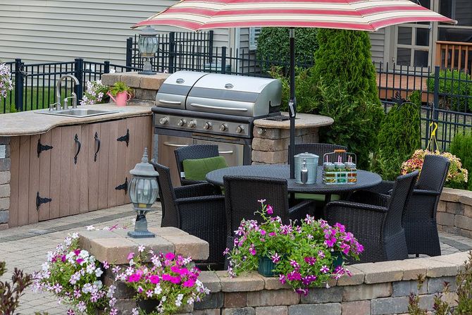 a patio with a grill, table, chairs and an umbrella