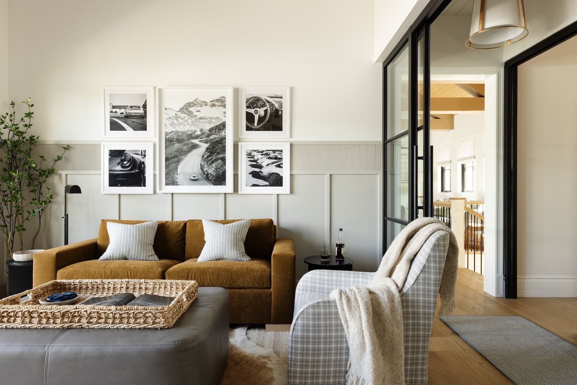 Modern living room with brown sofa, plaid chair, framed wall art, and warm natural light