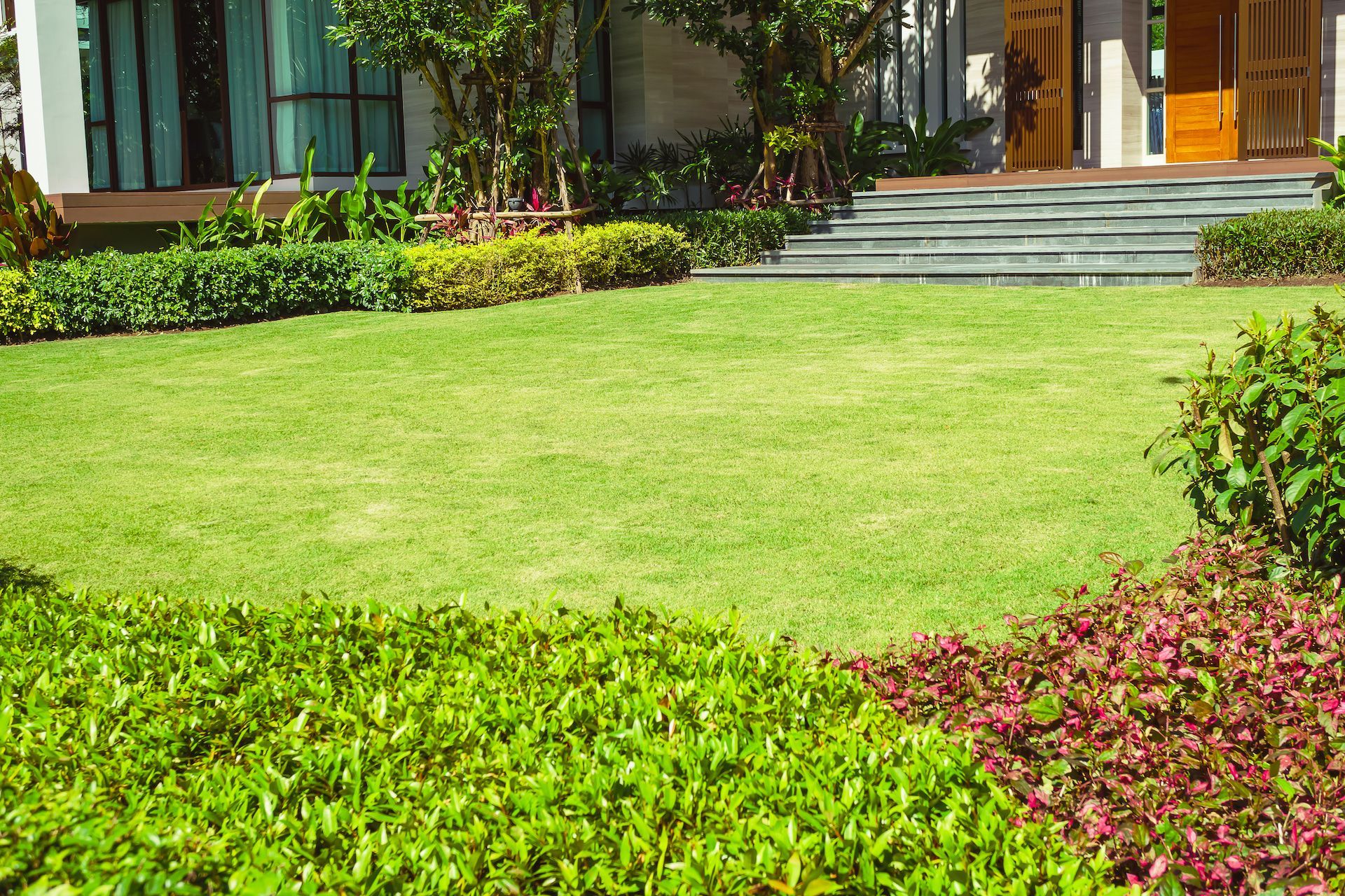 Lush green lawn with manicured bushes and a modern house with stone steps in the background — Chore Lovers in Caboolture, QLD