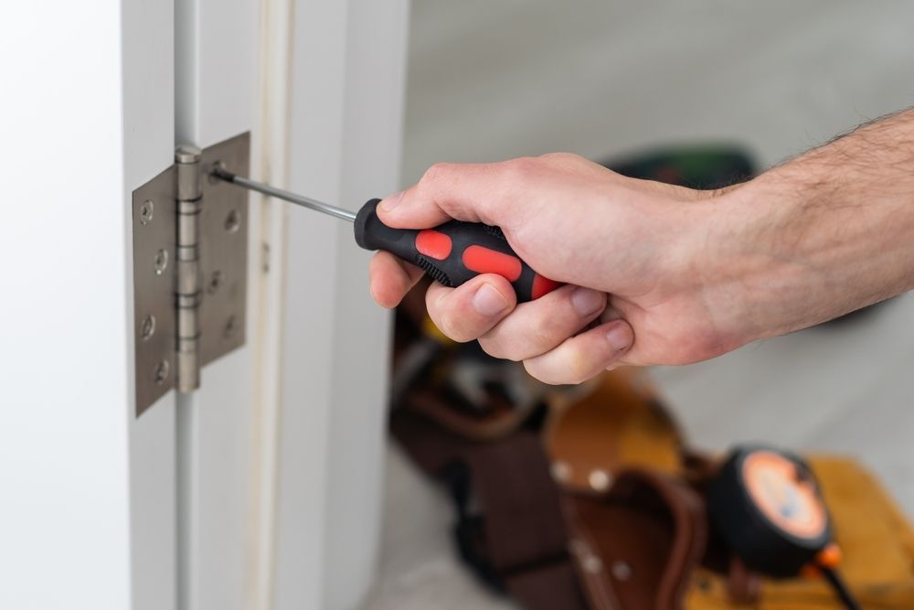 Person Using Screwdriver to Tighten Hinge on a White Door — Chore Lovers in Caboolture, QLD