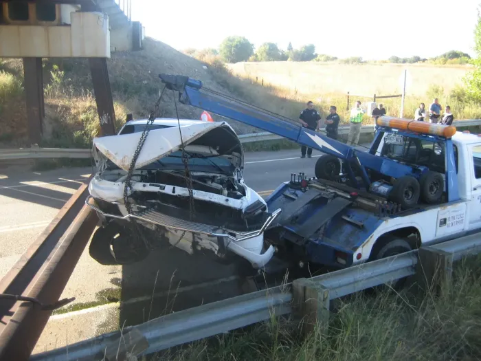 A blue and white tow truck is carrying a white car