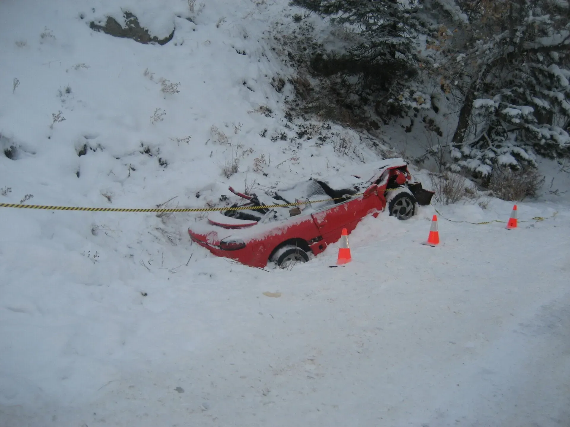 A red car is stuck in the snow on the side of the road
