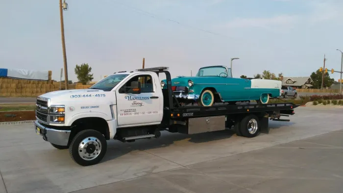 A tow truck is carrying a car on the back of it.