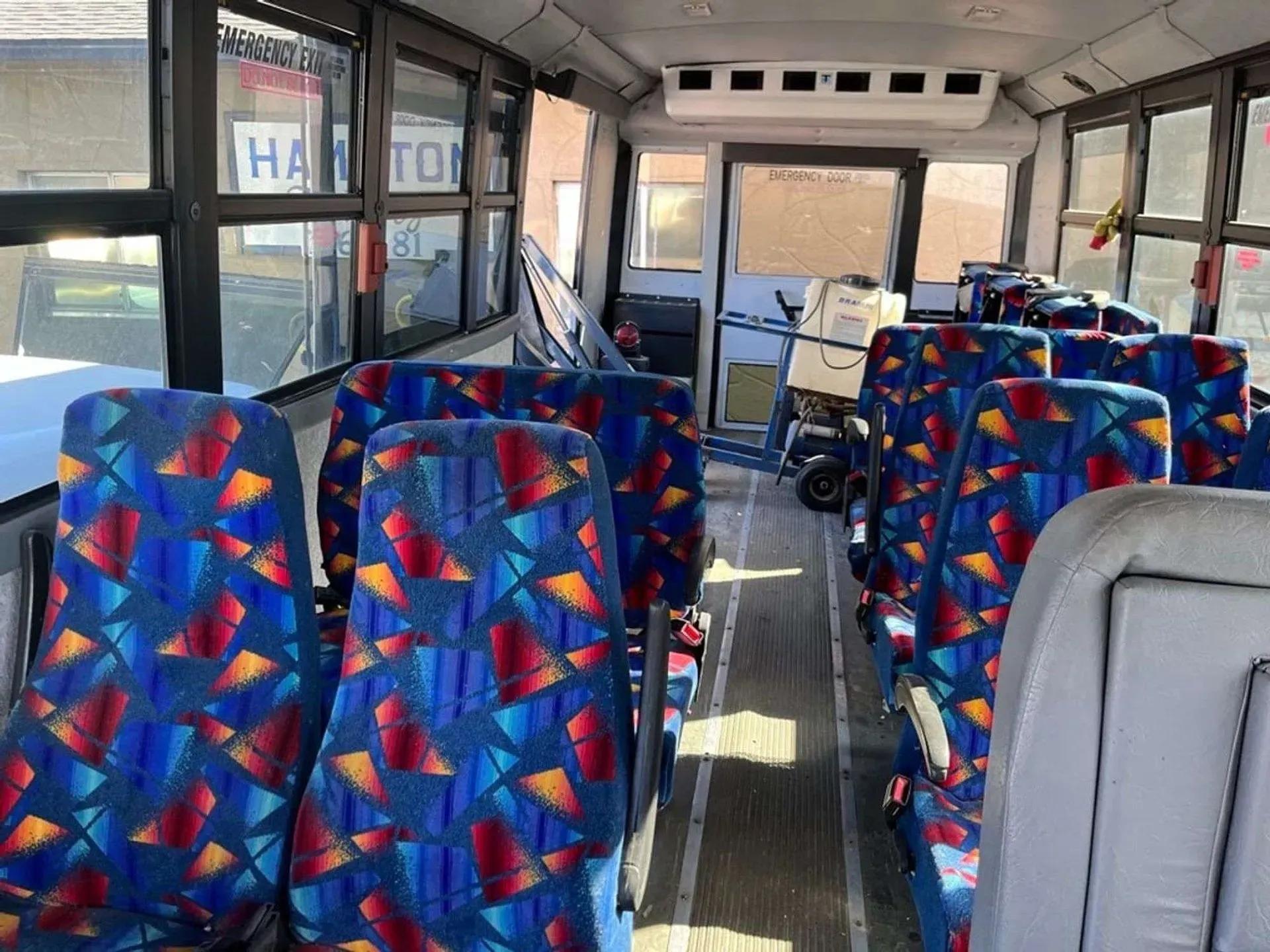 The inside of a bus with colorful seats and windows.