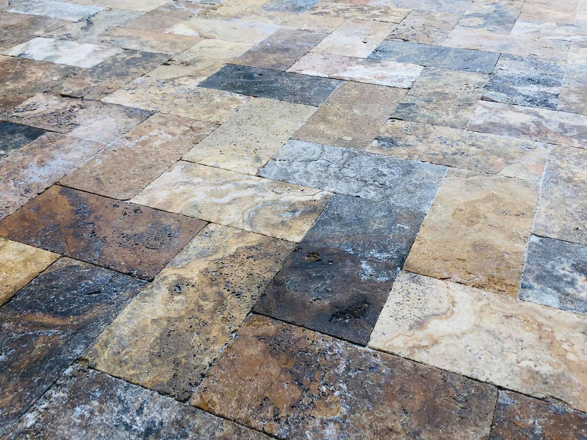 Multicolored stone tile floor with a mottled tan, gray, and brown pattern