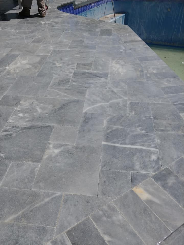 Gray stone walkway beside water, with a person partially visible at the top left.