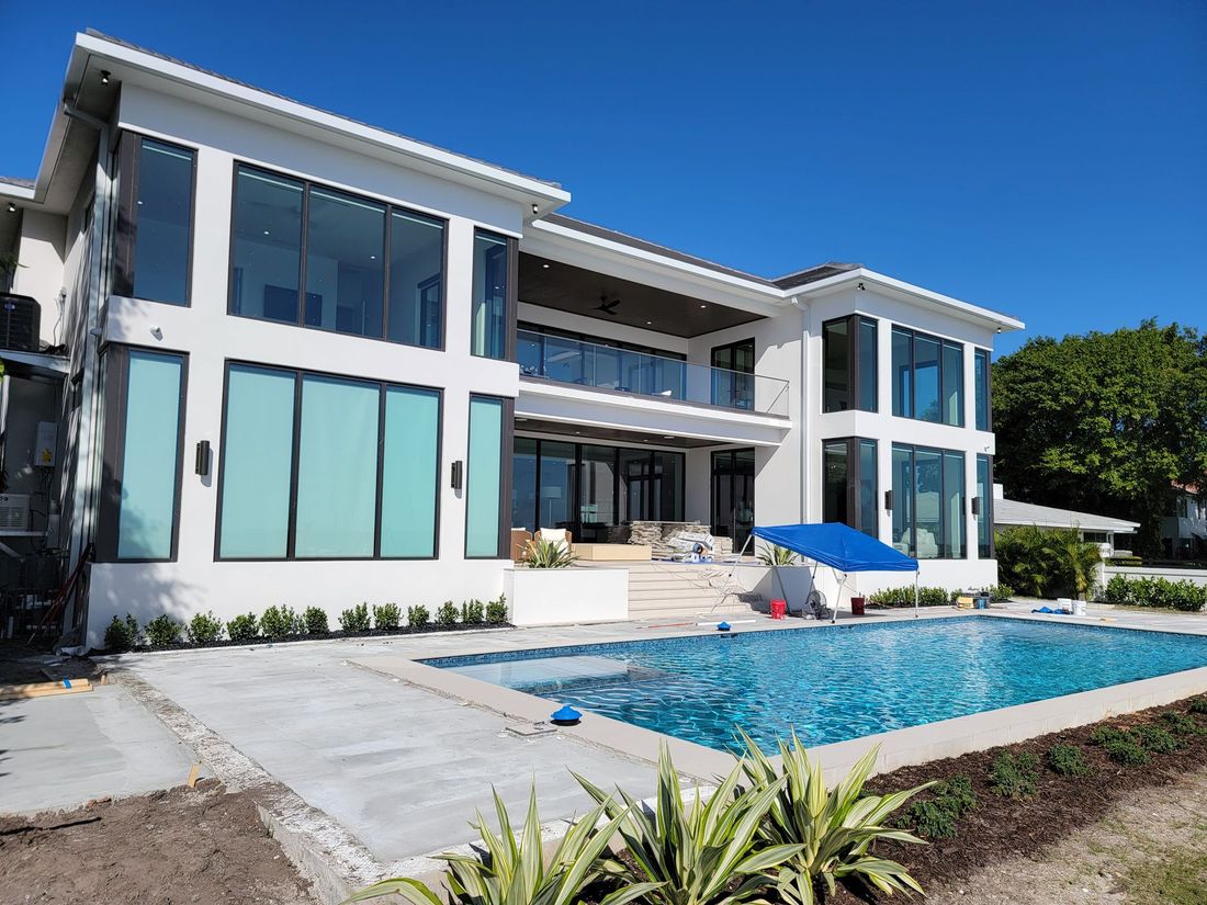 Modern white two-story house with large windows and a backyard swimming pool