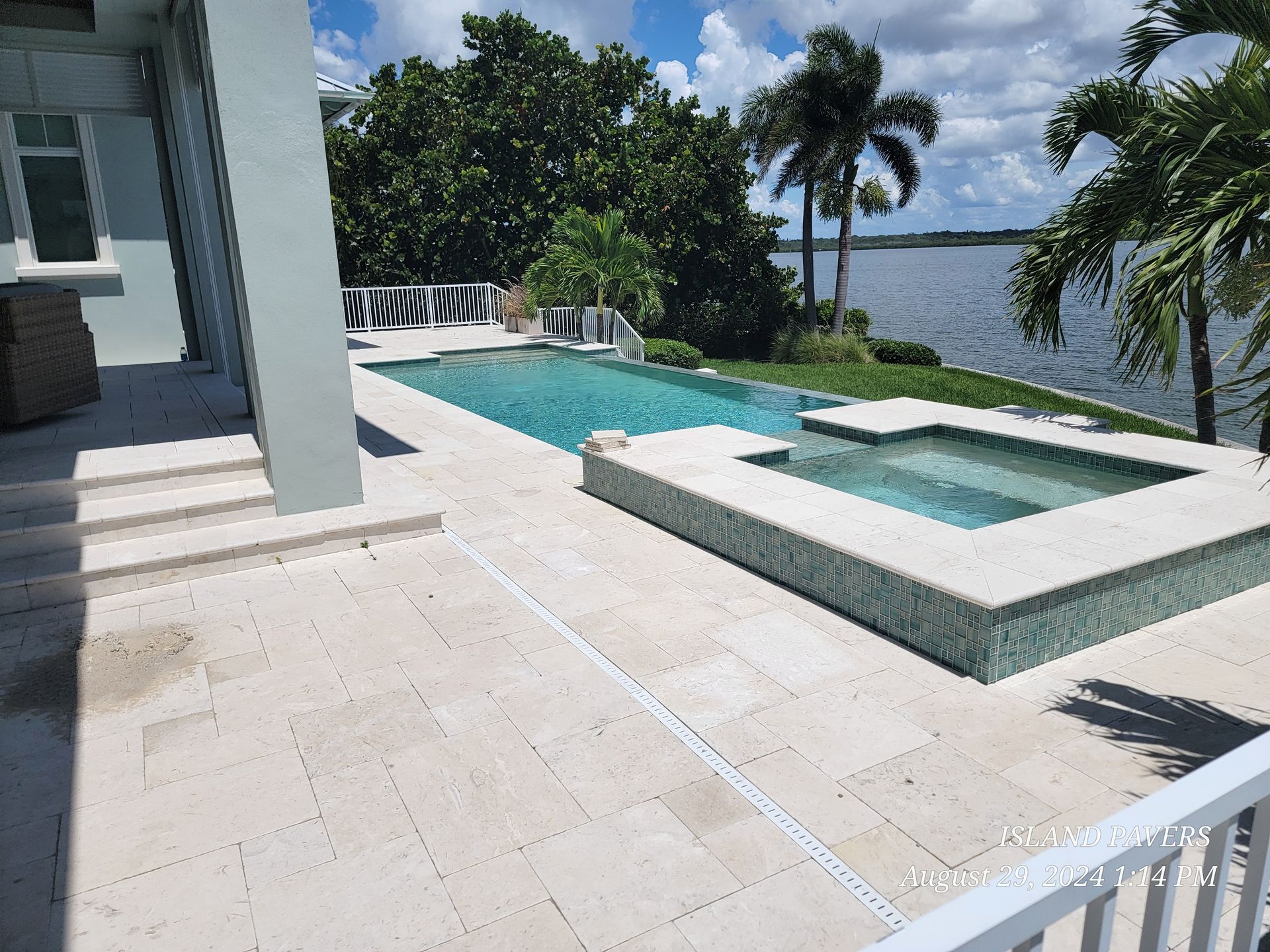 Luxury pool deck with a turquoise infinity pool and ocean view beside a white hot tub