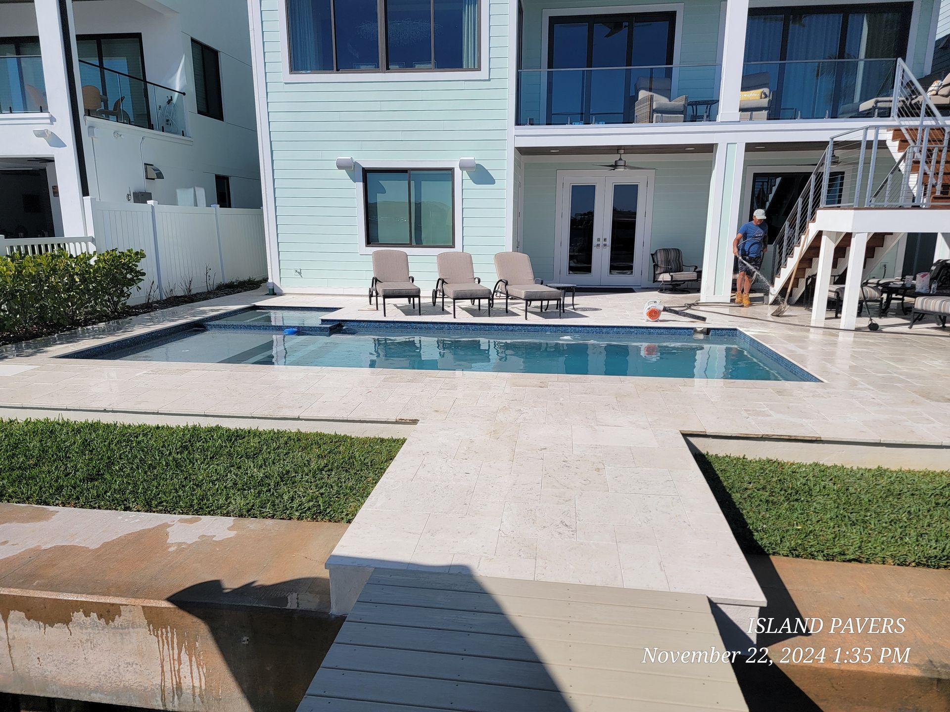 Modern apartment pool courtyard with lounge chairs, white buildings, and a small lawn walkway