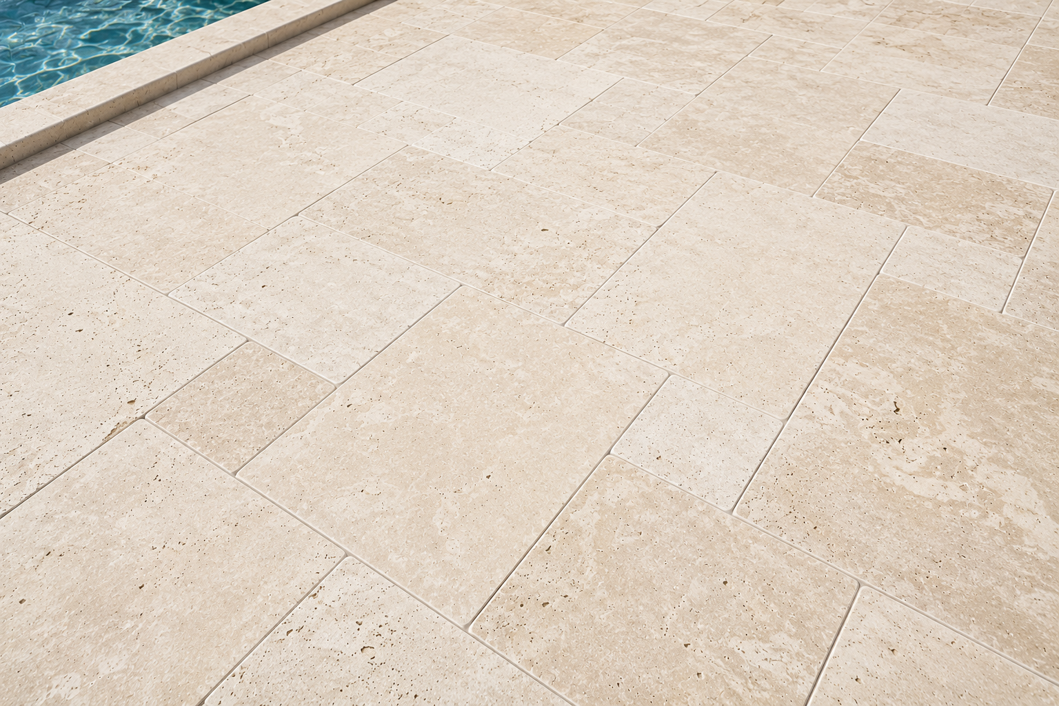 Beige stone poolside patio beside blue water