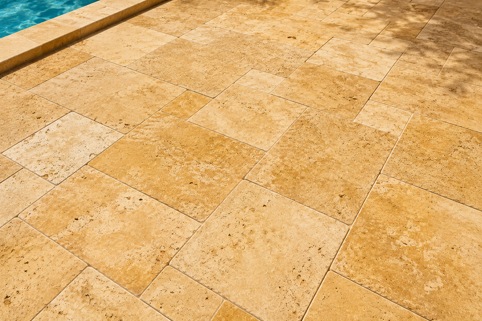 Beige stone patio tiles beside a turquoise pool edge