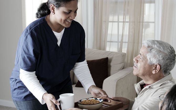 Carer serving a meal to older man